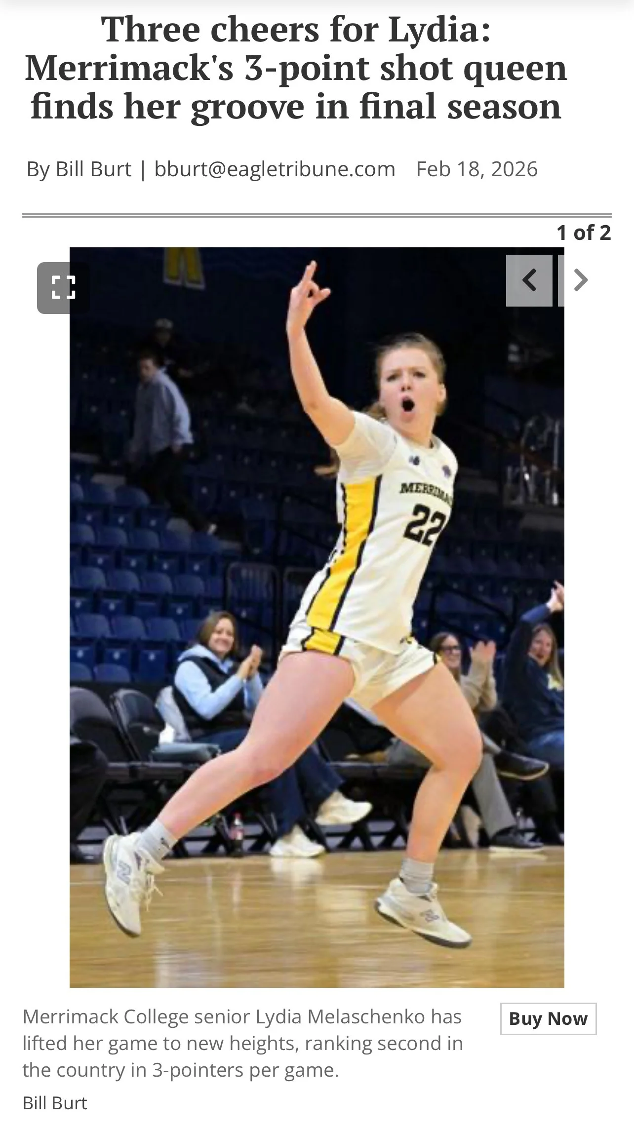 Merrimack College senior Lydia Melaschenko celebrating on a basketball court after a successful game, wearing a yellow and white uniform with the number 22, with spectators clapping in the background.