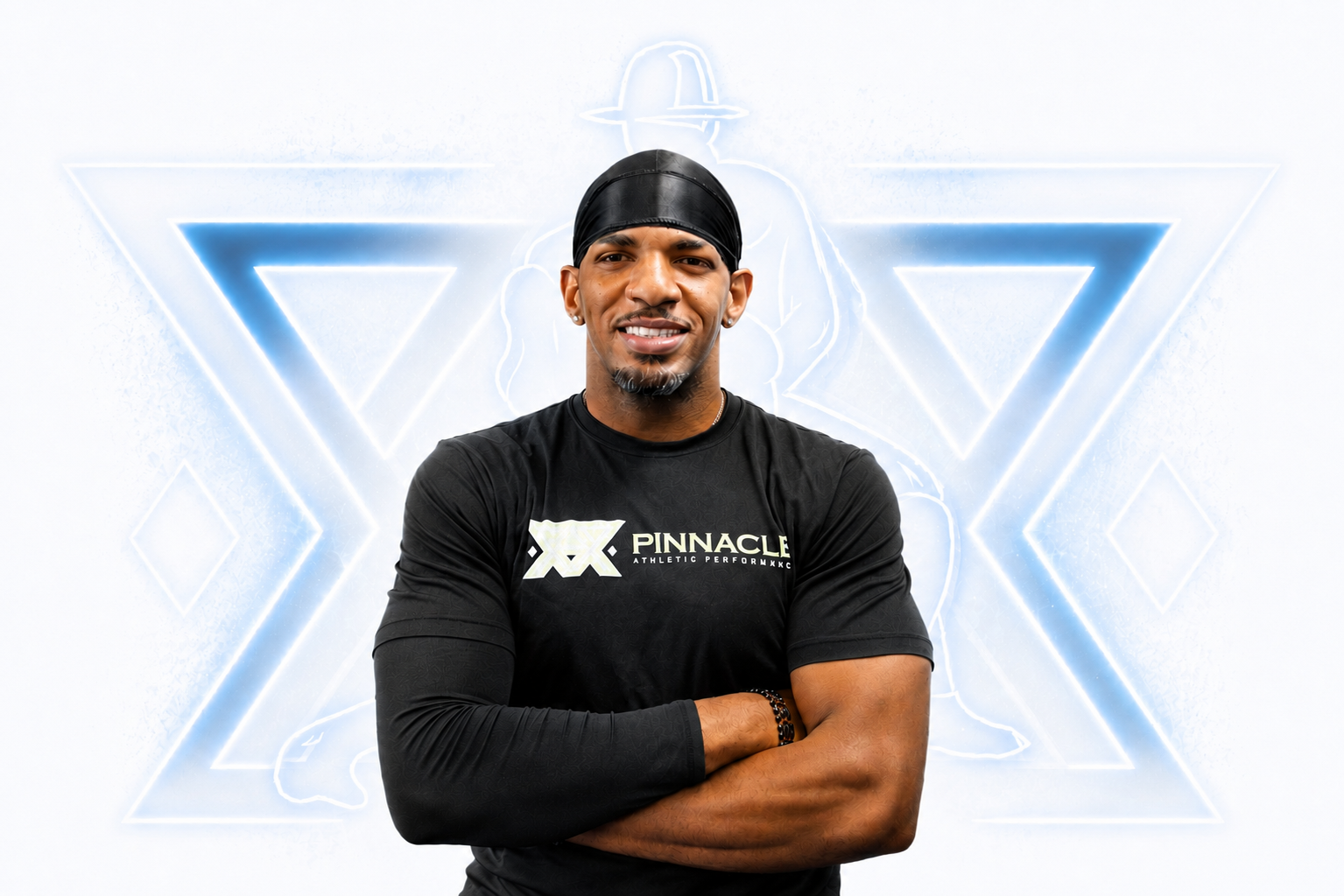 Man with arms crossed wearing a black Pinnacle Athletic Performance shirt and black head covering, standing in front of a wall with bright neon abstract geometric patterns.