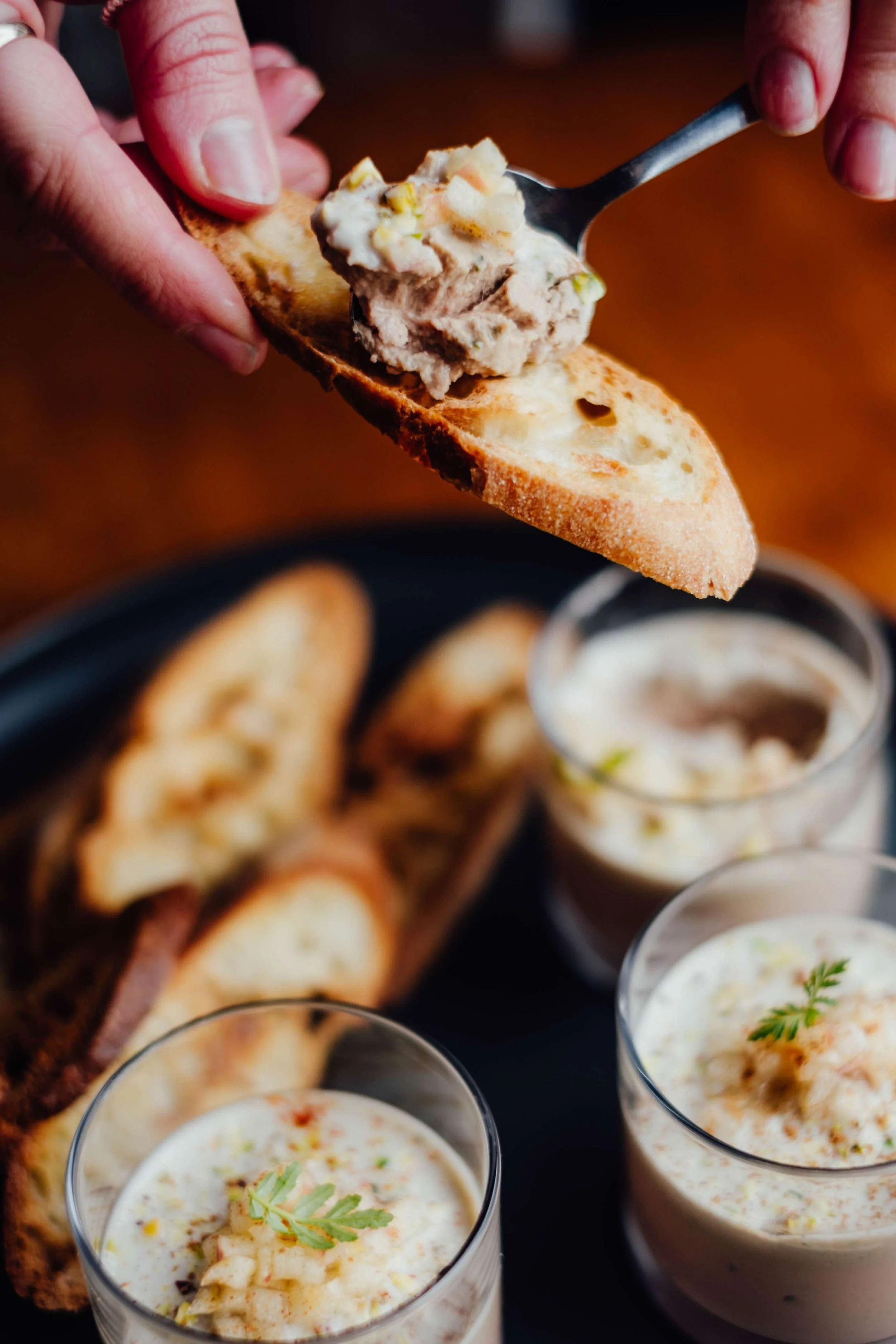 Des verres de crème fraîche ou un dip crémeux, garnis de herbes, accompagnant des tranches de pain grillé ou baguette.