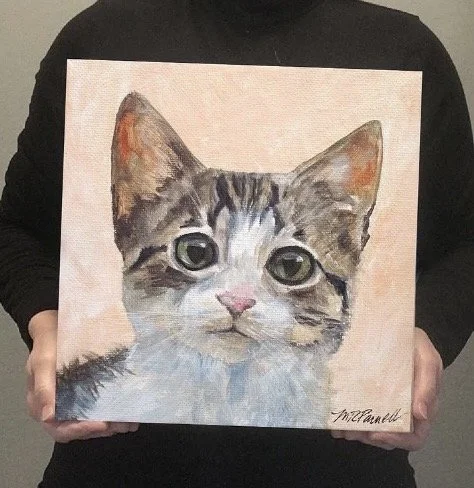 Person holding a 12x12 inch painting of a kitten on a peach background.