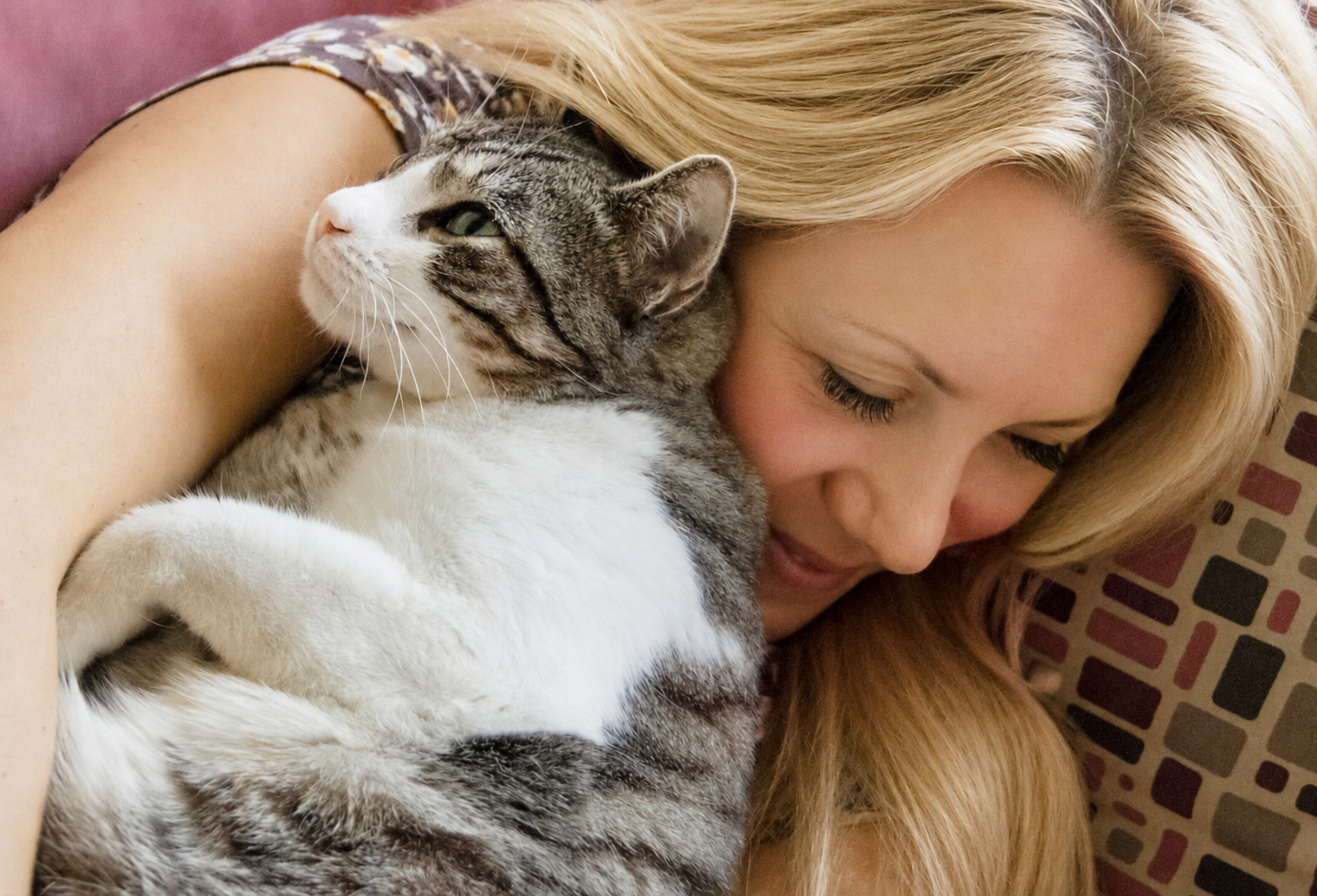 Photo of a woman cuddling a gray and white cat.