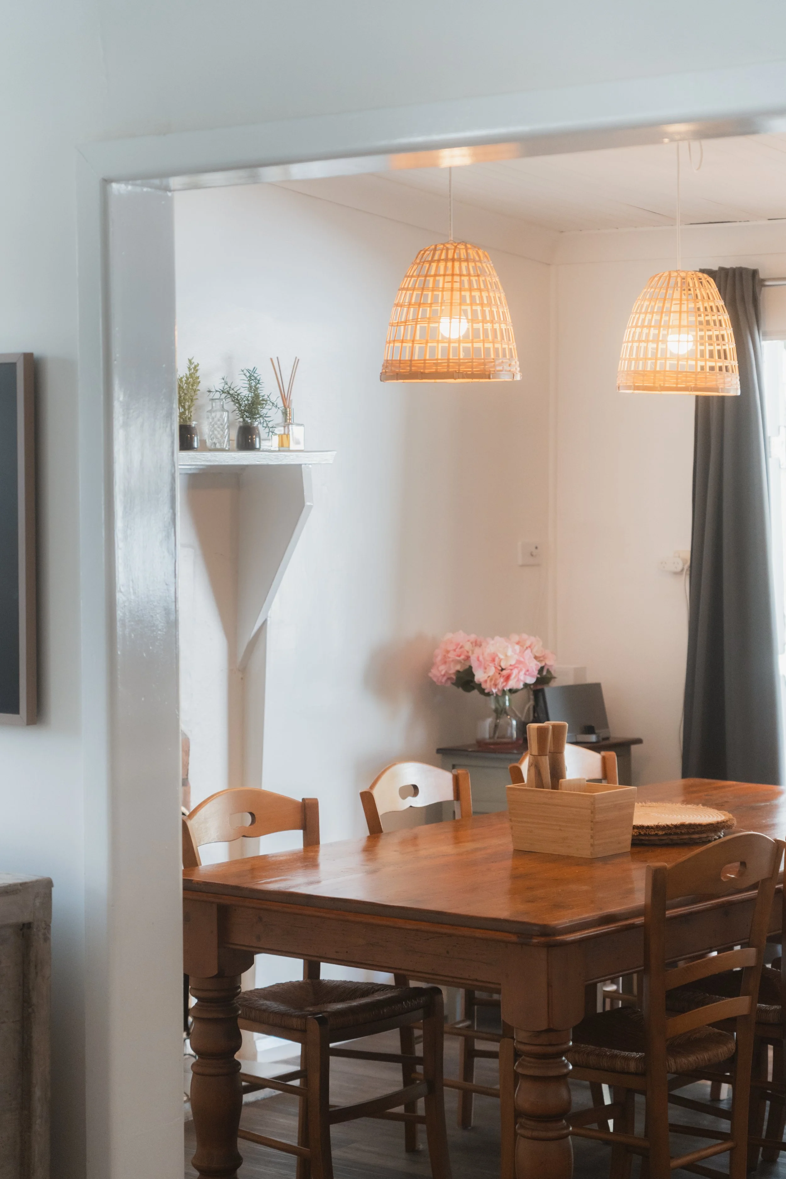 Dining room at Church Cottage Millthorpe with a timber table, woven pendant lights, white fireplace mantel and soft cottage-style décor.