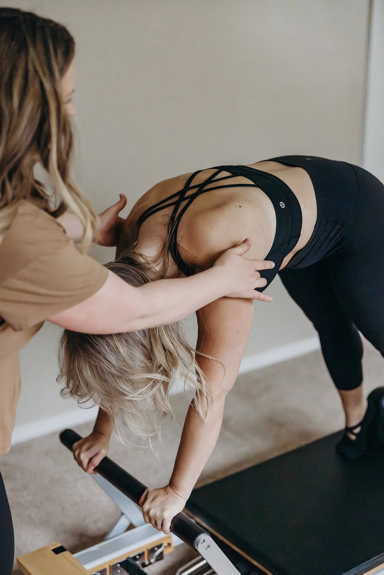Pilates instructor providing hands-on alignment support during a client’s standing forward stretch on a reformer at Liro Pilates in Anchorage, Alaska