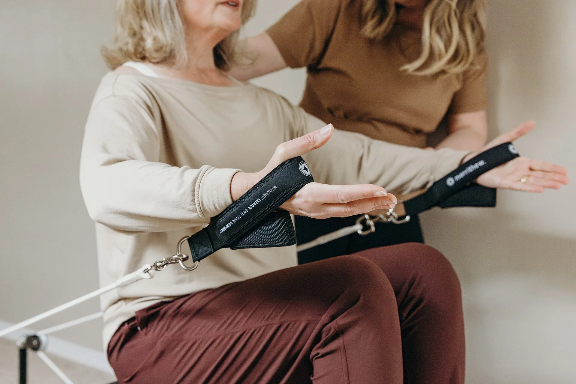 Pilates instructor guiding a client through resistance strap arm exercises during a private reformer session at Liro Pilates in Anchorage, Alaska