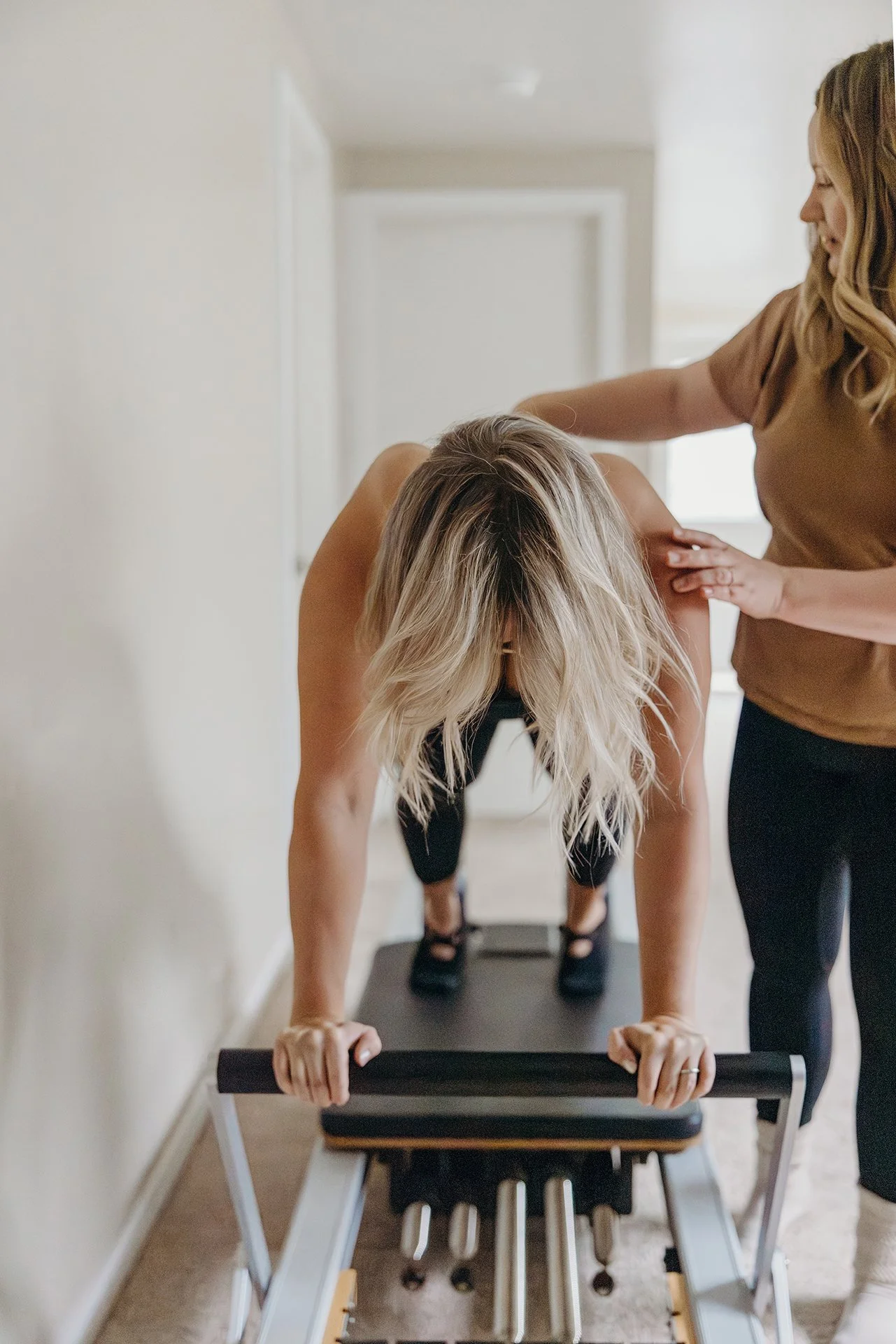 Pilates instructor guiding a client’s alignment during a standing reformer exercise at Liro Pilates in Anchorage, Alaska