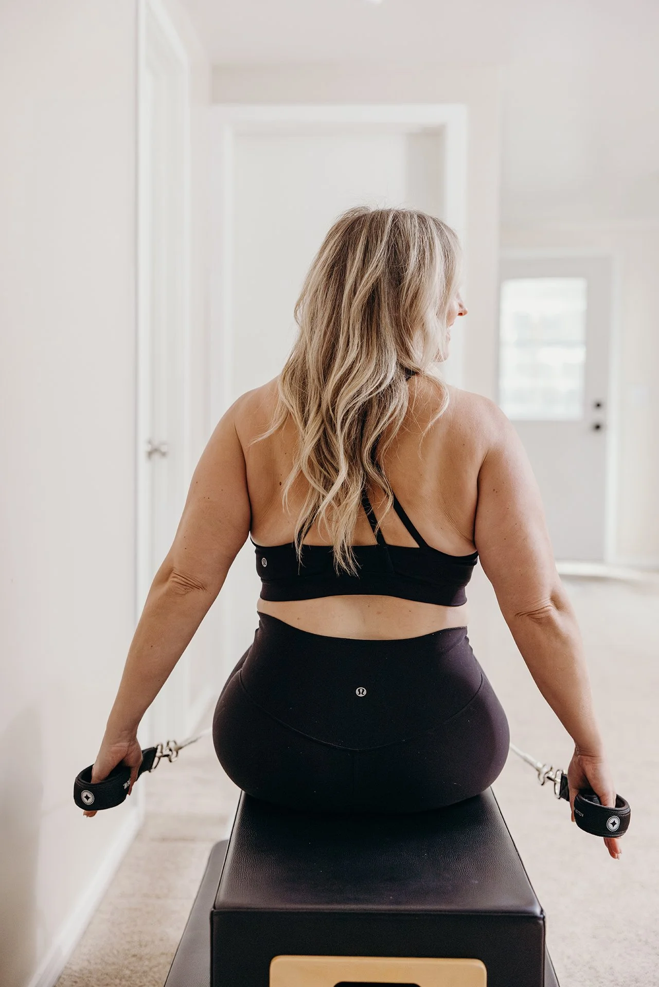 Woman seated on a Pilates reformer using resistance straps at Liro Pilates in Anchorage, Alaska