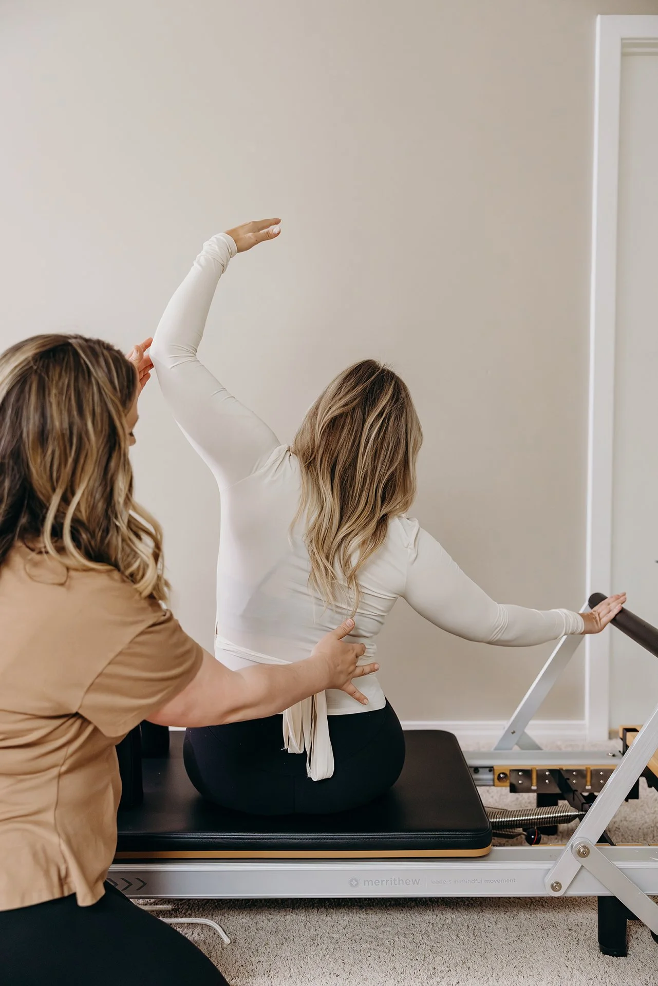 Pilates instructor guiding a client through a seated reformer stretch at Liro Pilates in Anchorage, Alaska