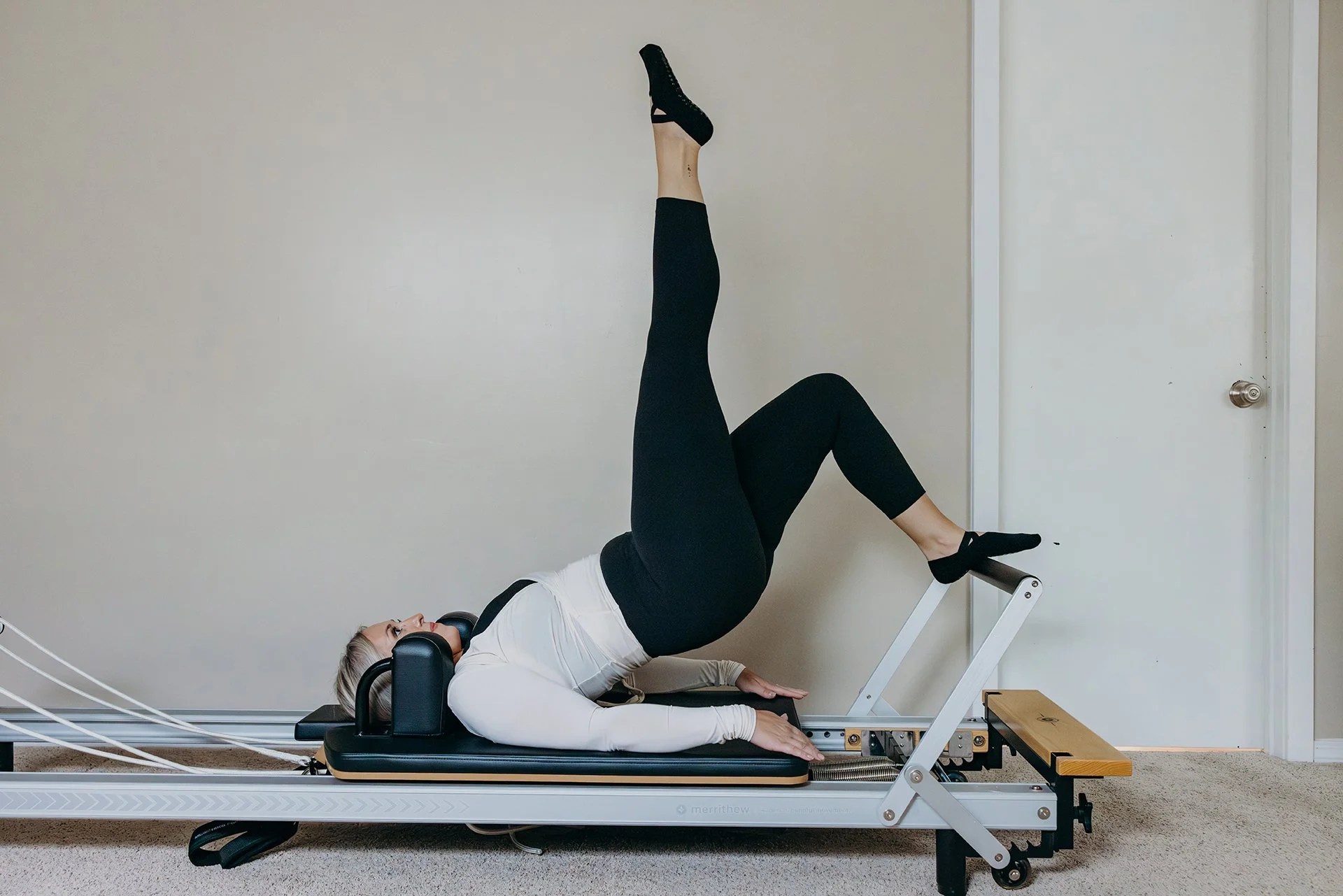 Woman performing a single-leg bridge exercise on a Pilates reformer at Liro Pilates in Anchorage, Alaska
