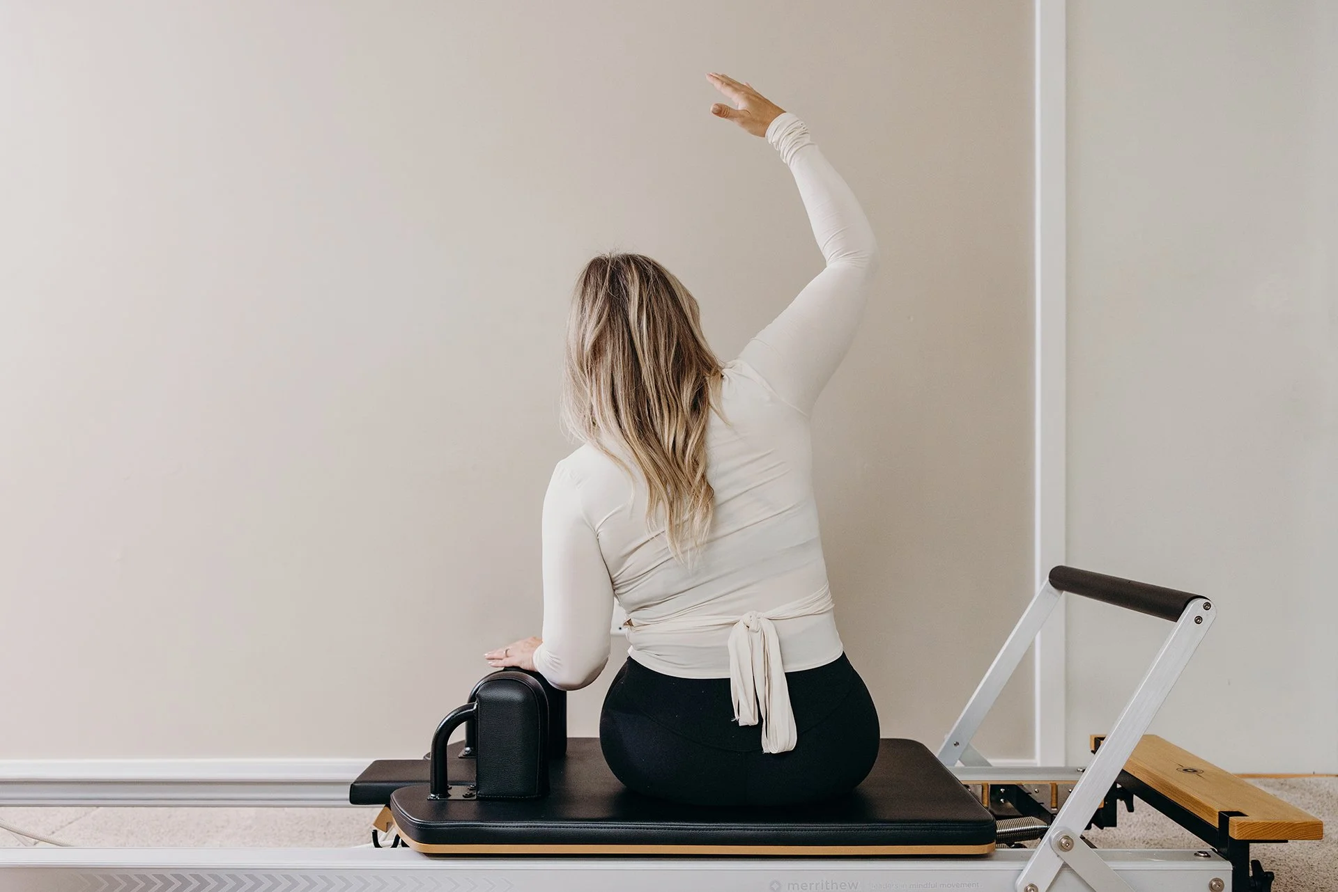 Woman performing a seated side stretch on a Pilates reformer at Liro Pilates in Anchorage, Alaska
