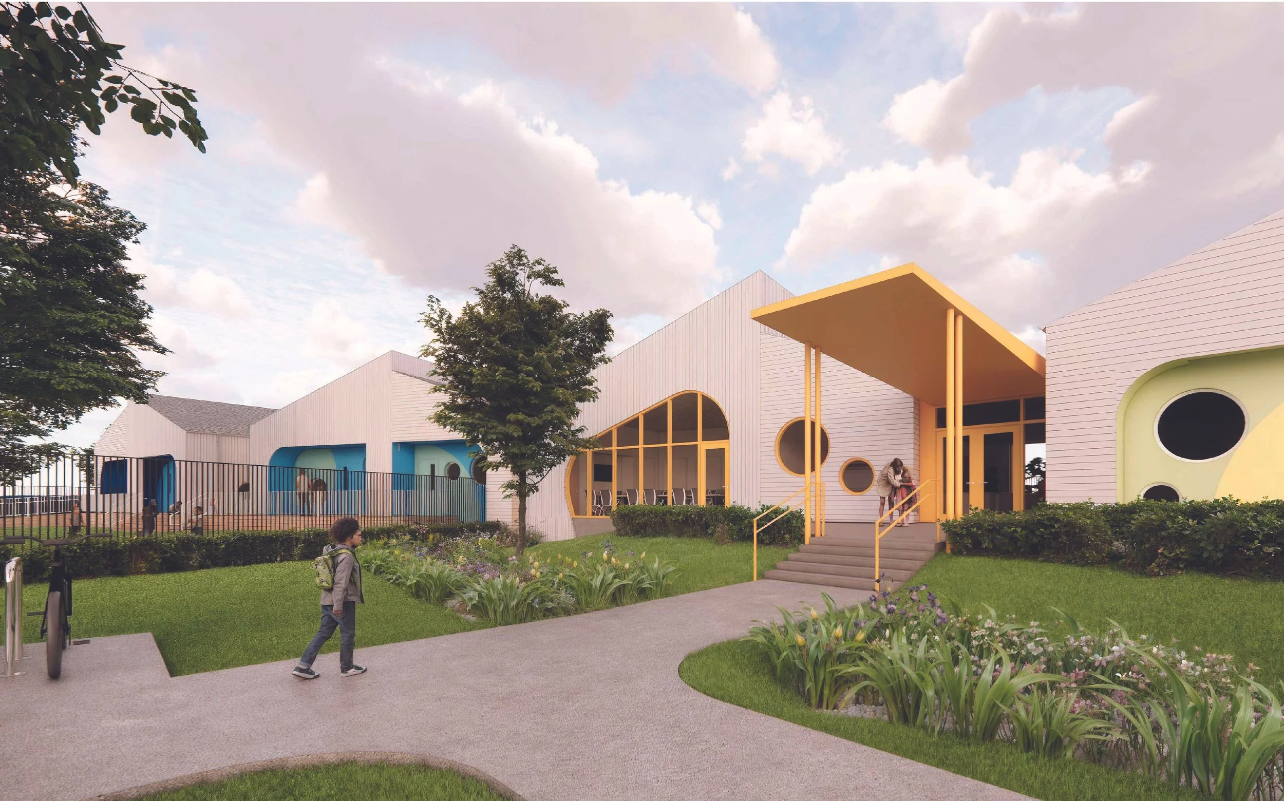 Colorful modern building with blue, yellow, and green accents, surrounded by a well-maintained garden with flowers and shrubs, children playing, and a person walking along a paved path under a cloudy sky.