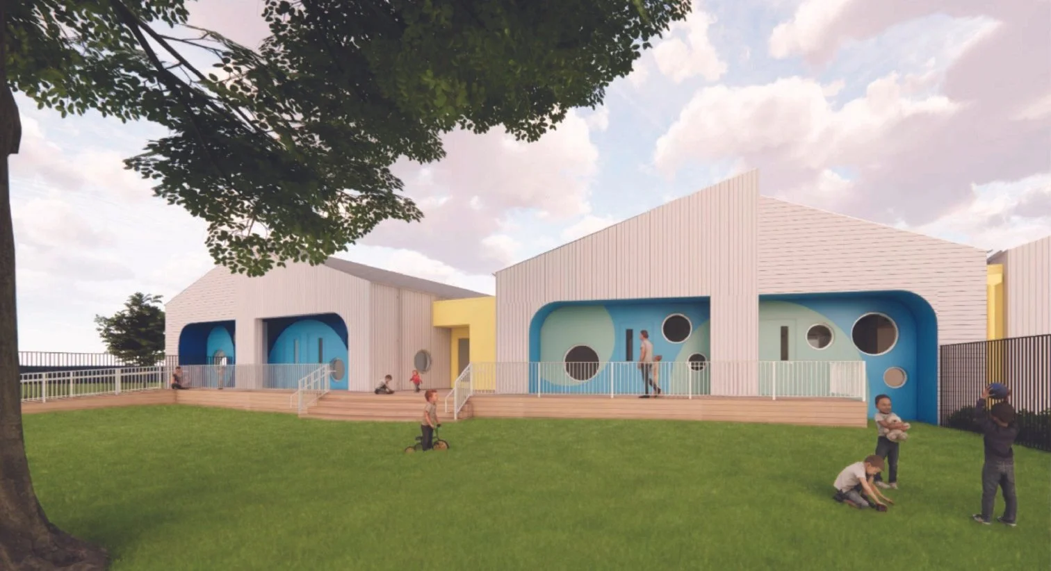 Modern playground building with curved blue and green painted walls, surrounded by a grassy area with children playing and adults supervising, under a partly cloudy sky.