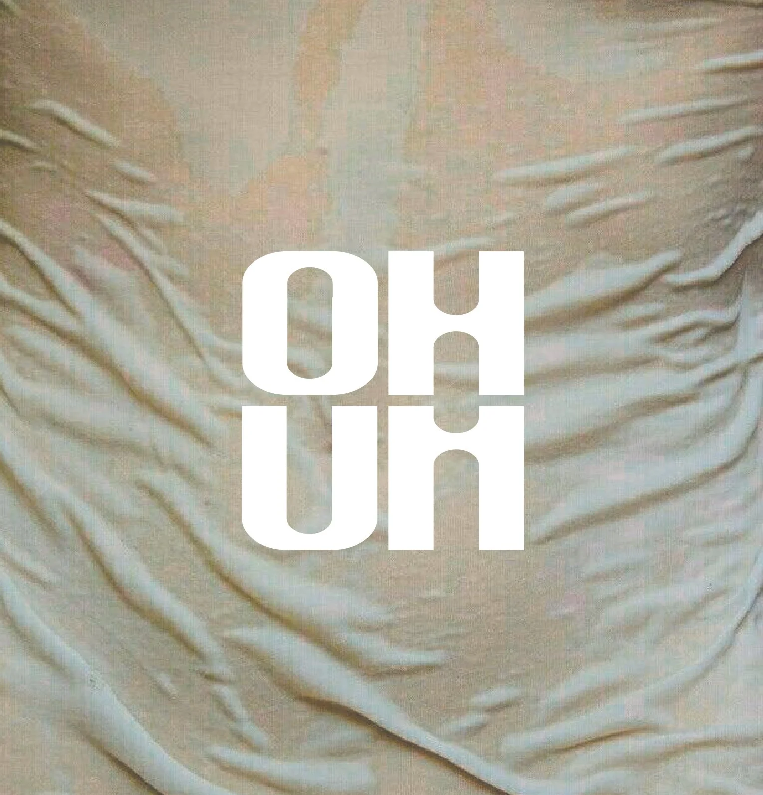Close-up of beige fabric with white text overlay that reads 'OHUM' in large bold letters.