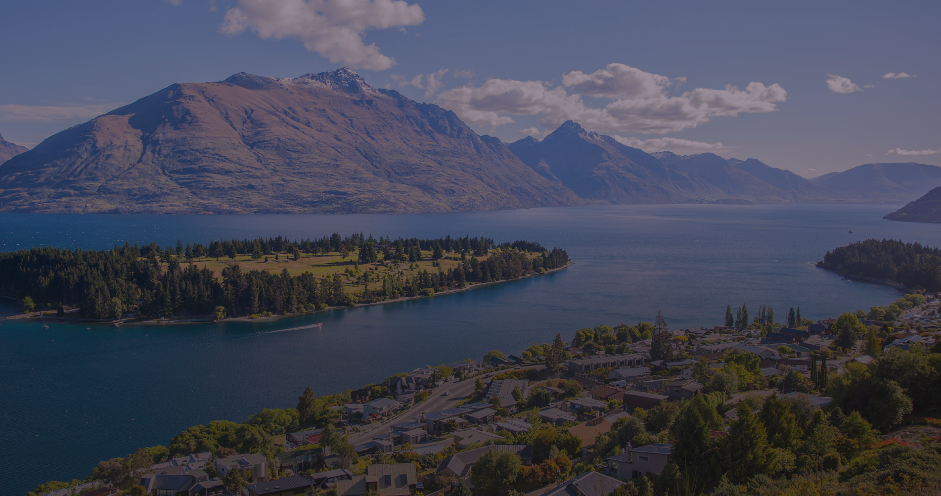 Aerial view of a lake surrounded by mountains and residential area showcasing Civil Construction in Queenstown NZ