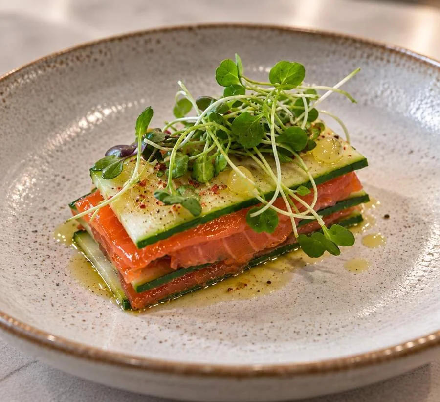 Layered salmon and cucumber starter with microgreens.