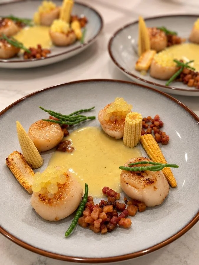 Seared scallops with corn and seasonal accompaniments.