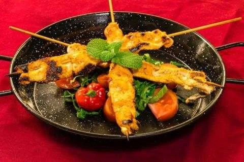 Grilled skewers served with fresh vegetables.