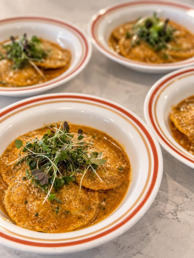Ravioli in golden sauce topped with microgreens.