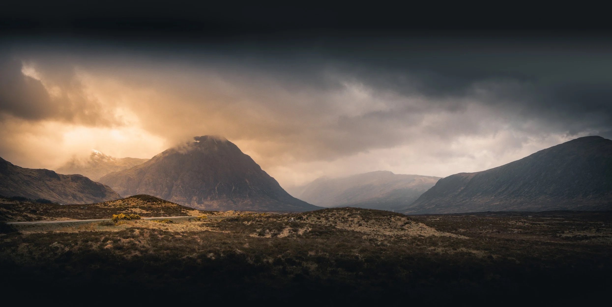 Dramatic light breaking through storm clouds over the Scottish Highlands, photographed from the A82 in Scotland.