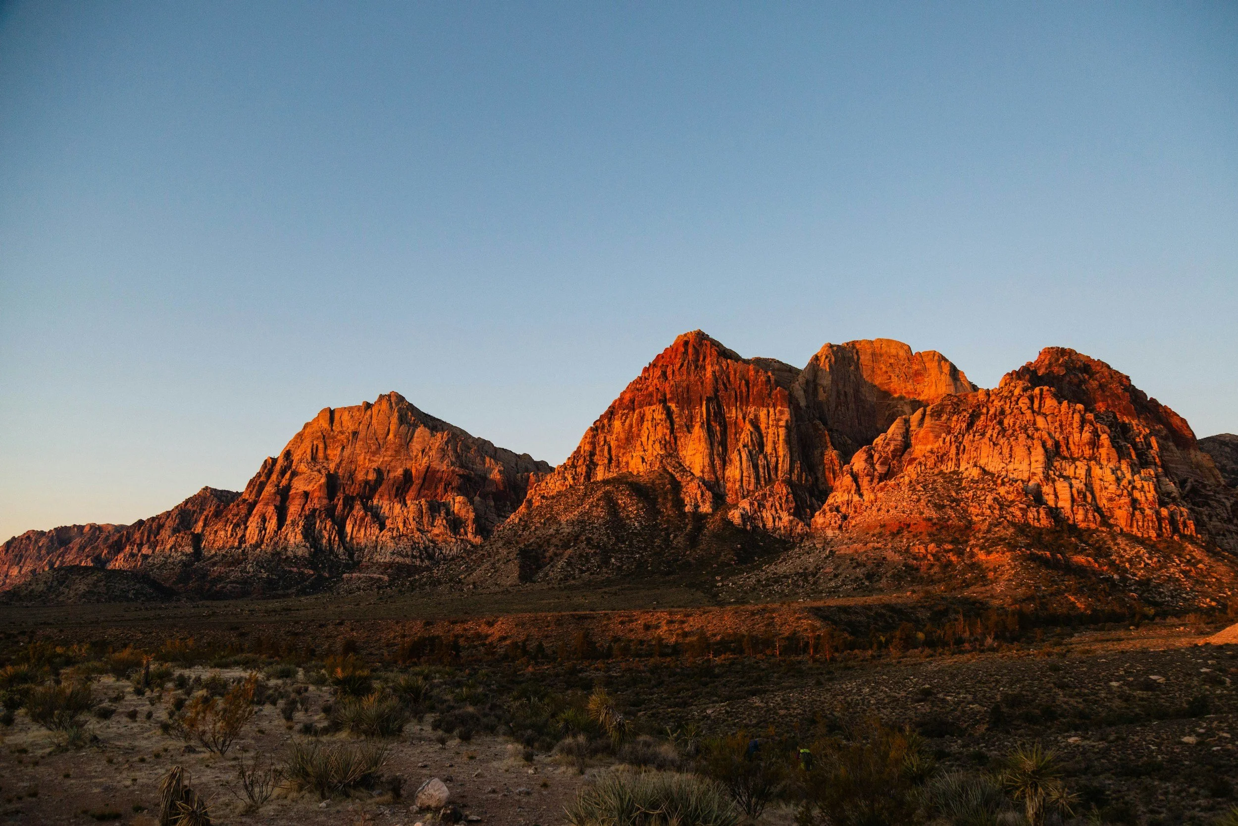 Sunset illuminating rugged mountain peaks in a desert landscape.