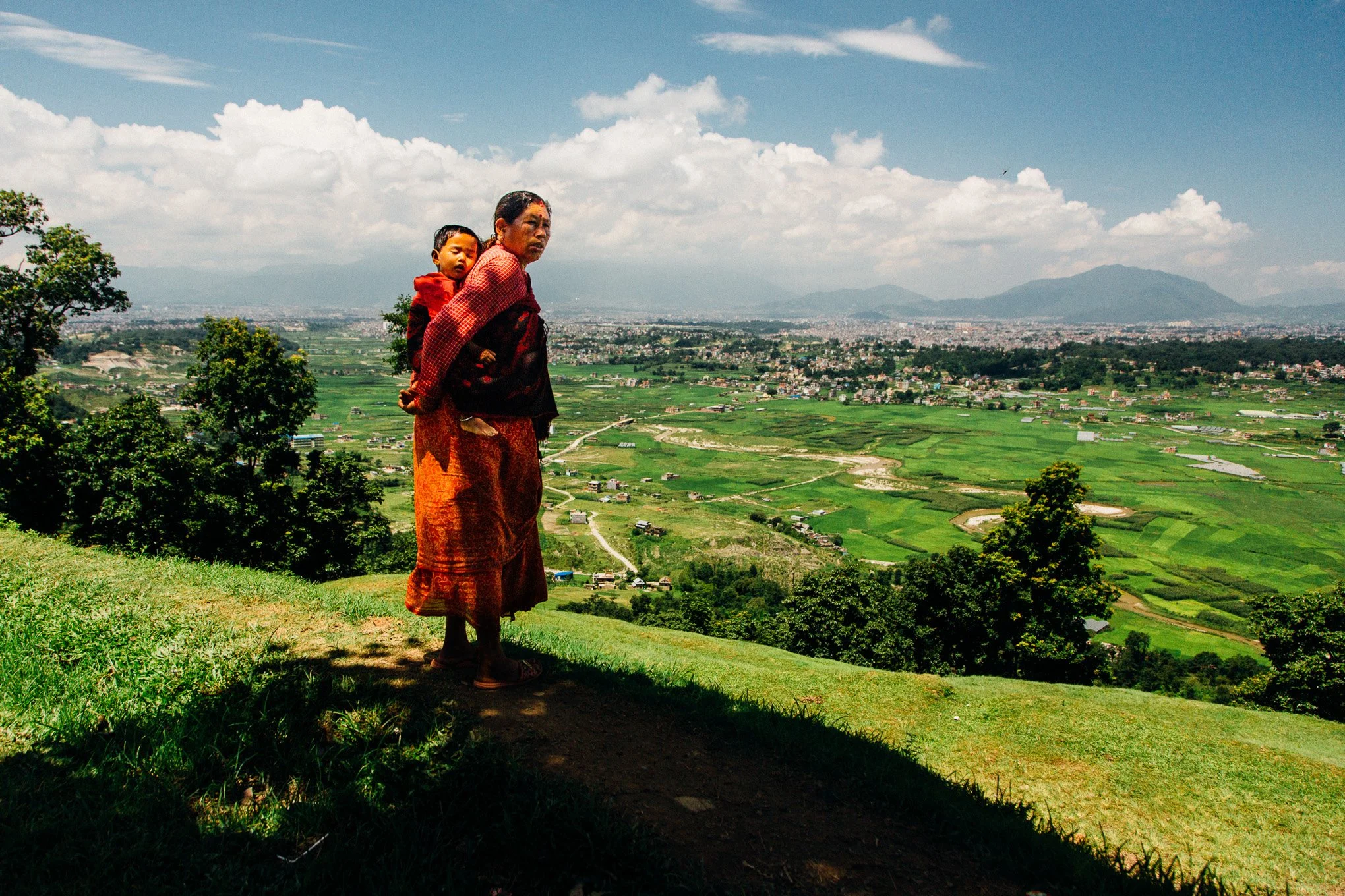 A mother carrying her child looks toward Kathmandu Valley from Nagarkot in Nepal.