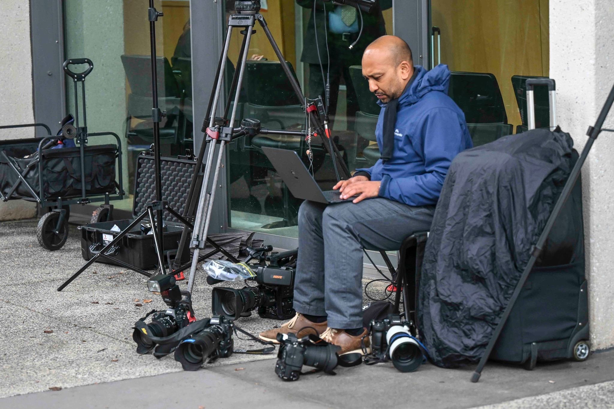 Melbourne photojournalist Asanka Brendon Ratnayake working on a laptop beside cameras, lenses and video equipment during an assignment.