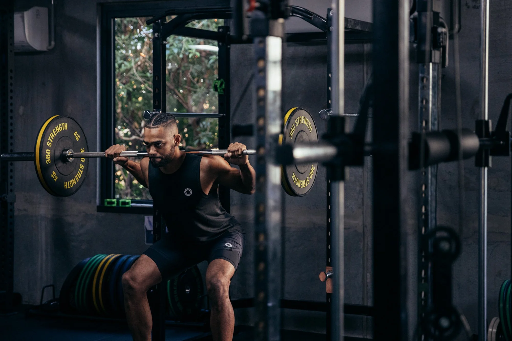 A man performs a barbell squat inside a gym during a fitness lifestyle shoot.