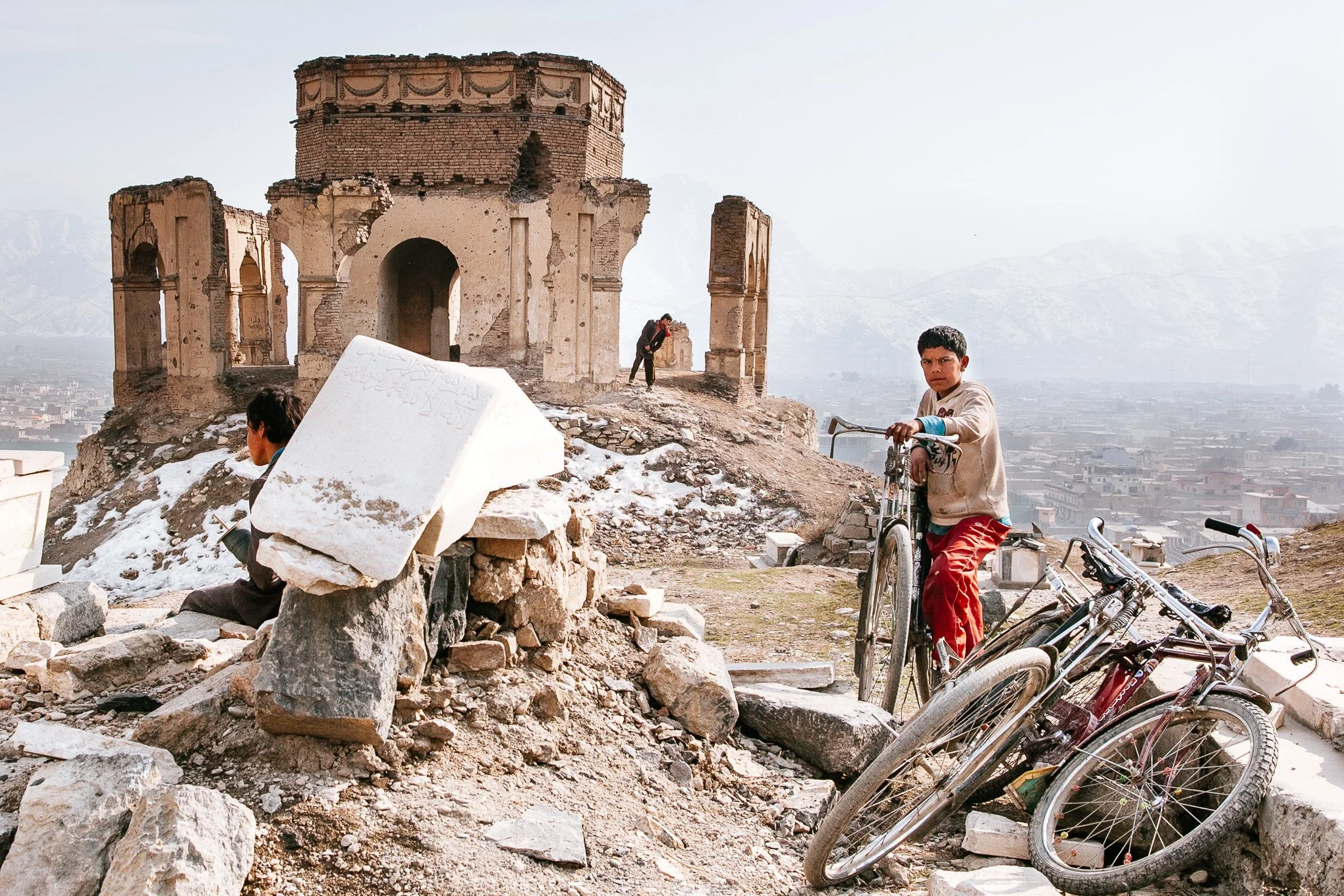 A boy holds onto his bicycle outside the ruined King Zahir Shah's tomb Kabul Afghanistan 
