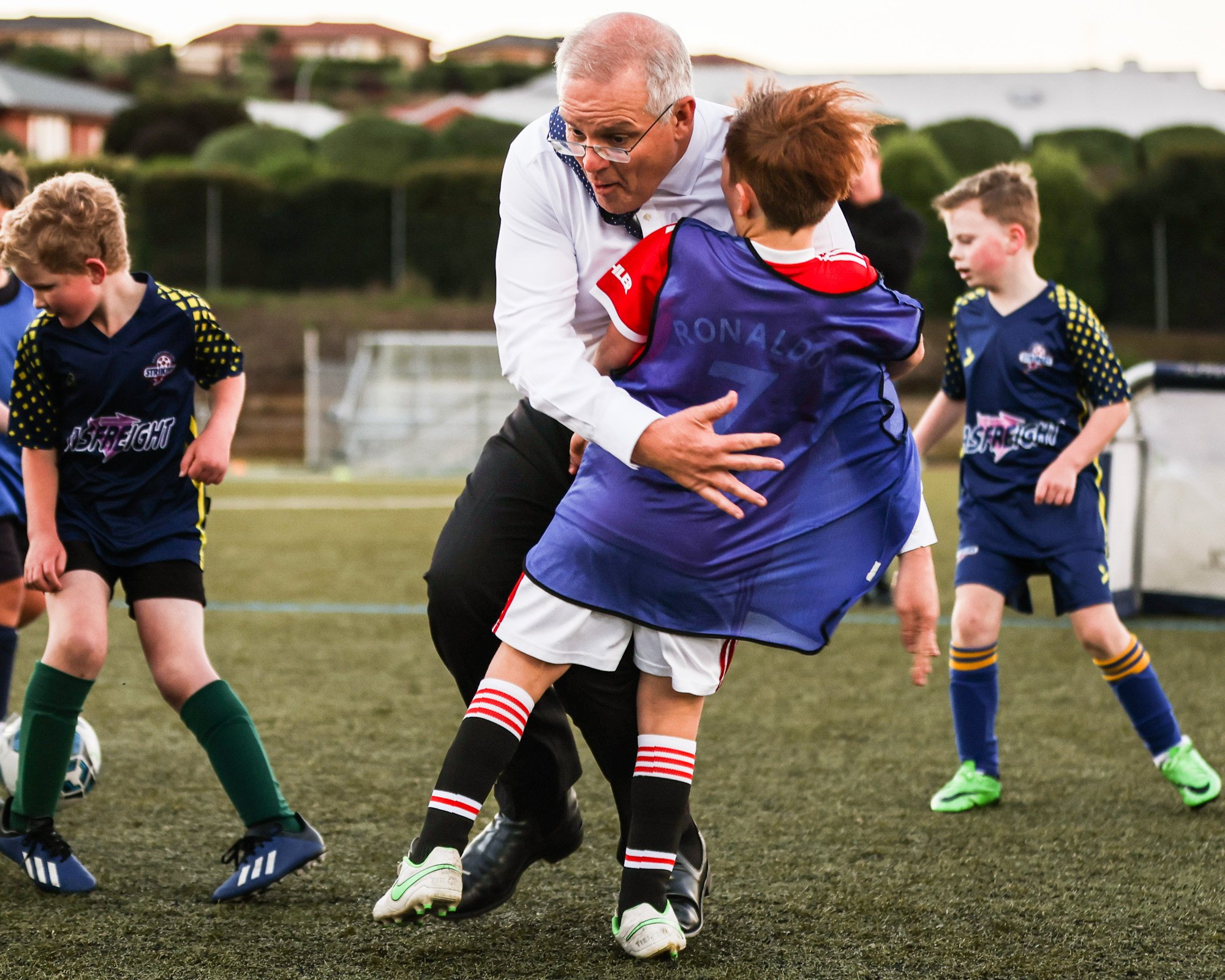 Scott Morrison tackles a junior soccer player during the 2022 federal election campaign.