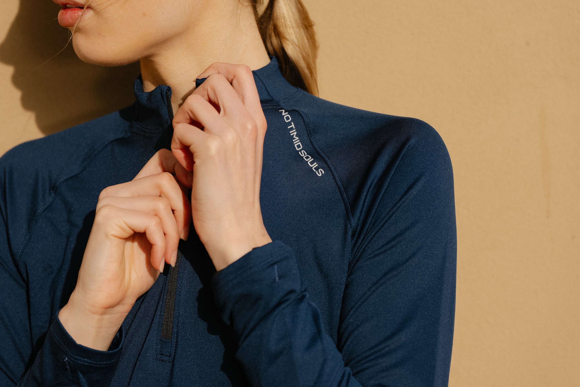 Close up of a woman adjusting the zip on a blue activewear top.