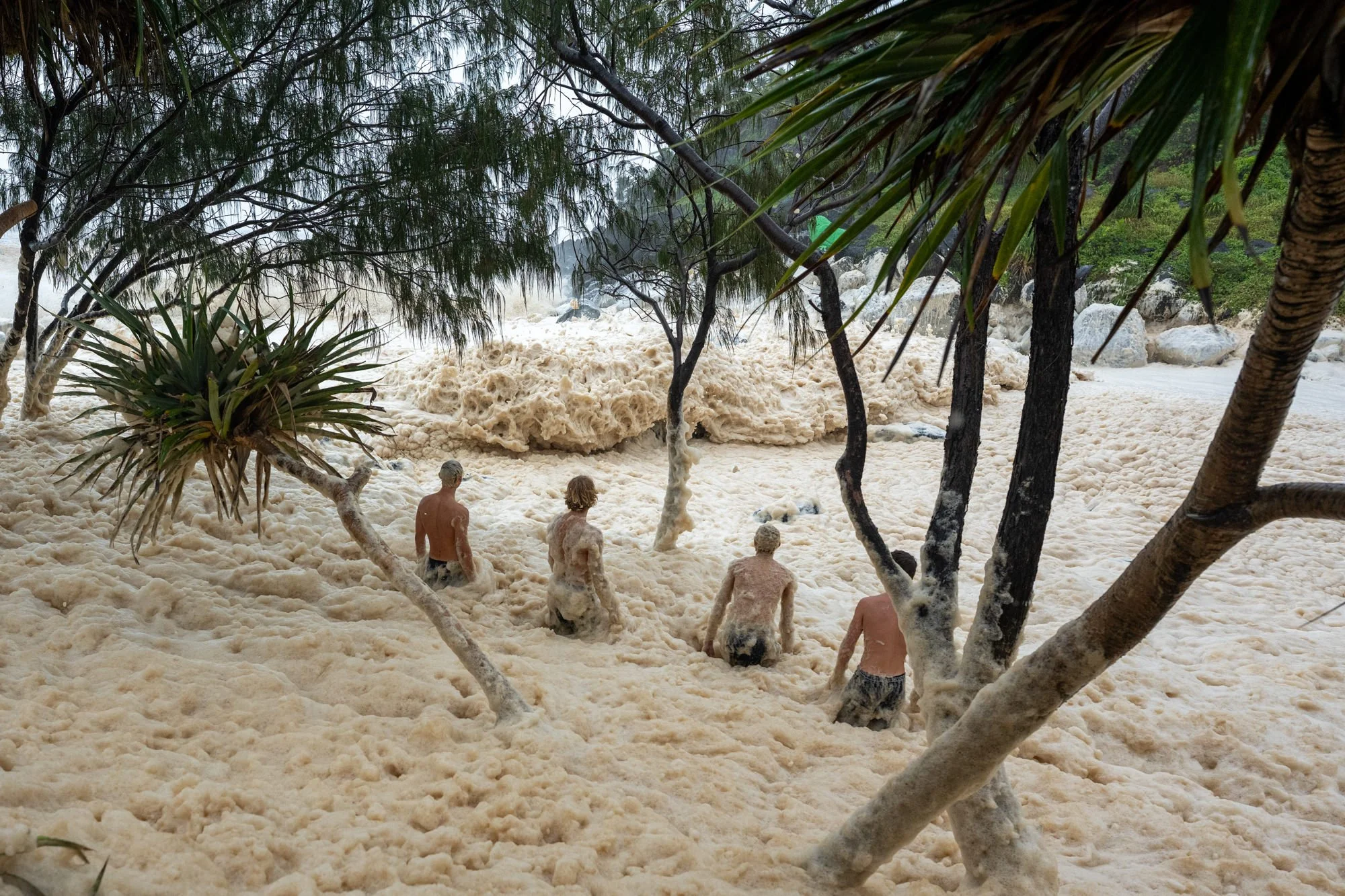 People walk through sea foam at Tweed Heads after Tropical Cyclone Alfred.