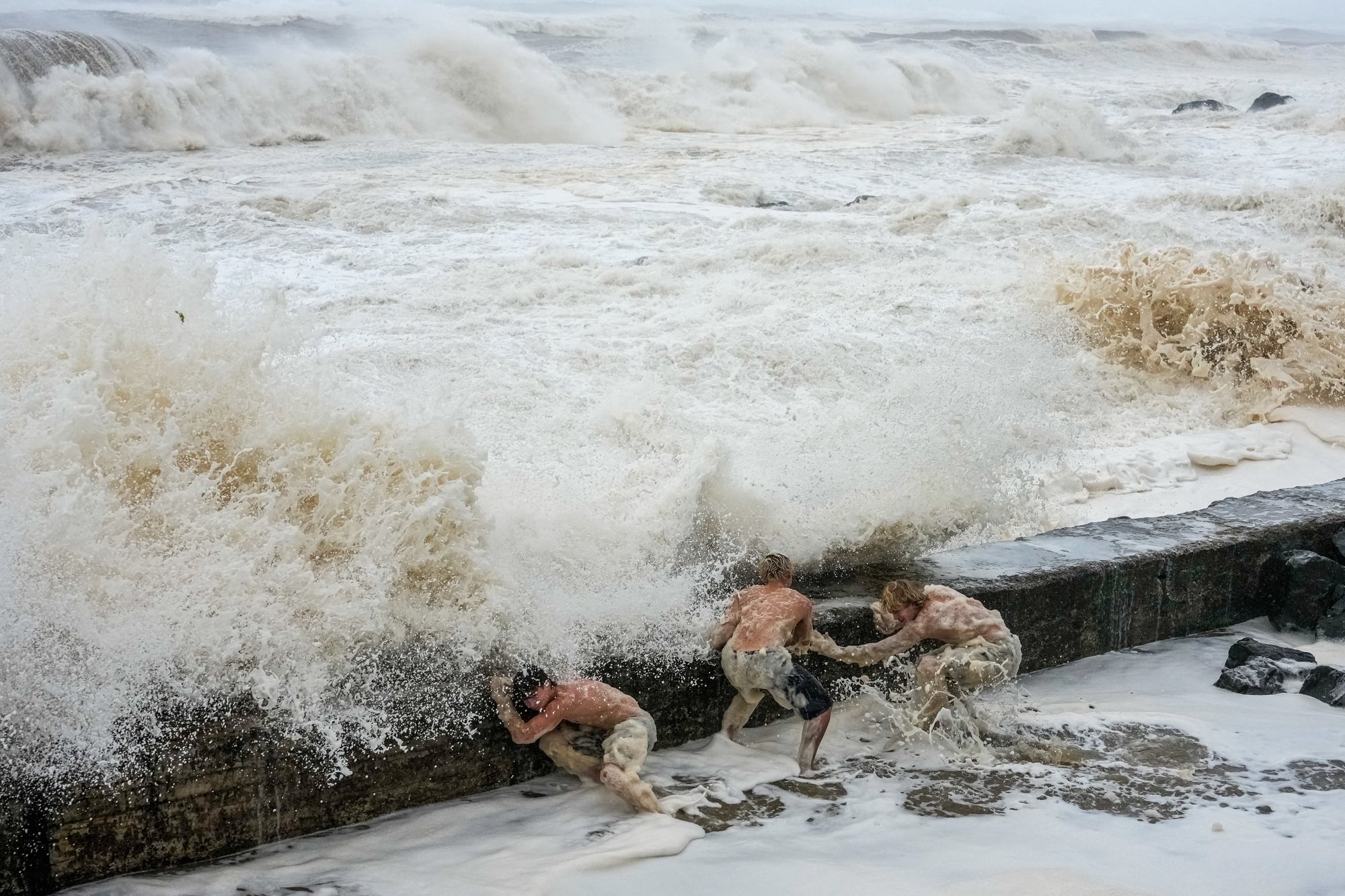 People evade a crashing wave at Tweed Heads ahead of Tropical Cyclone Alfred.