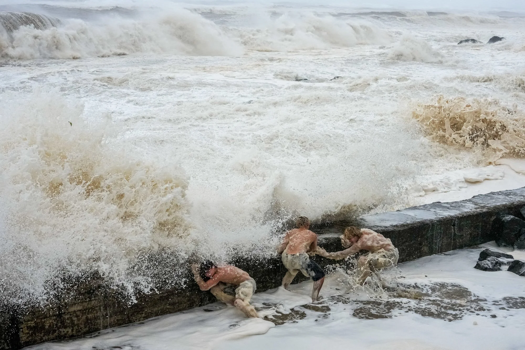 People evade a crashing wave at Tweed Heads ahead of Tropical Cyclone Alfred.
