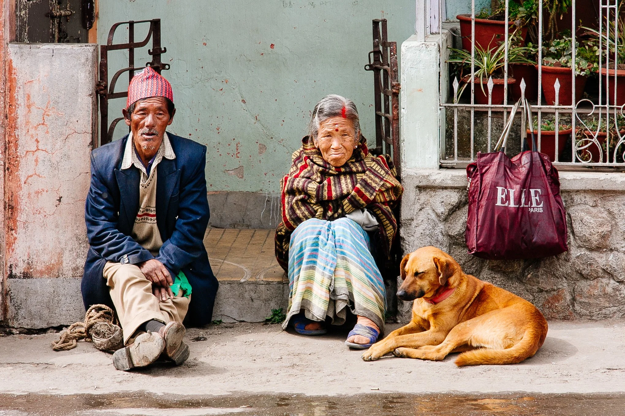 An elderly couple sit on their front porch next to a dog in Darjeeling West Bengal India