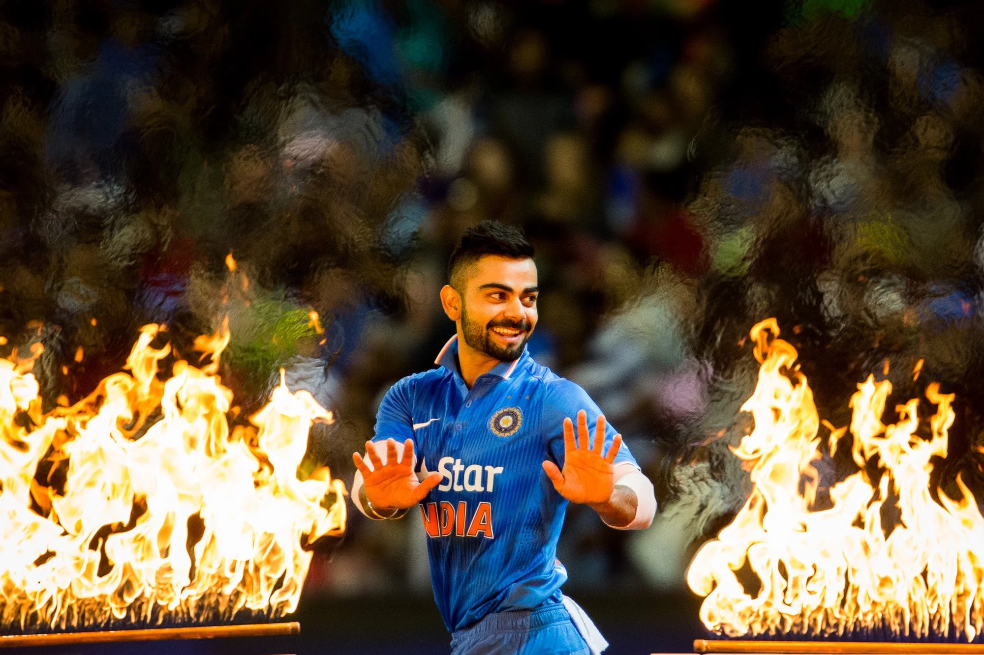 Virat Kohli warms his hands as he walks past the flames during the T20 cricket at the MCG
