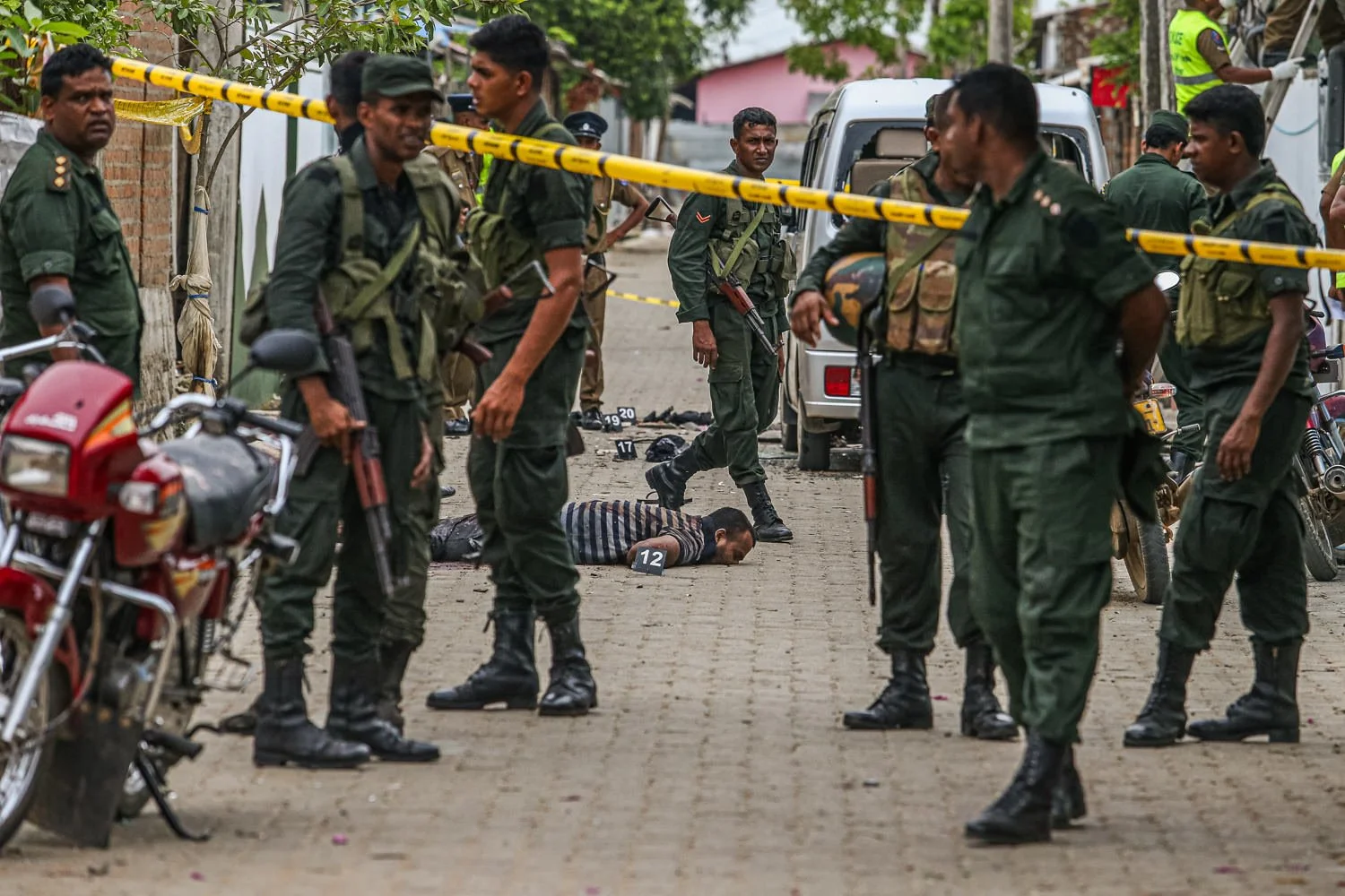 Sri Lankan army soldiers stand at a crime scene in Sainthamaruthu where a body lies on the ground after a raid on a suspected hideout.