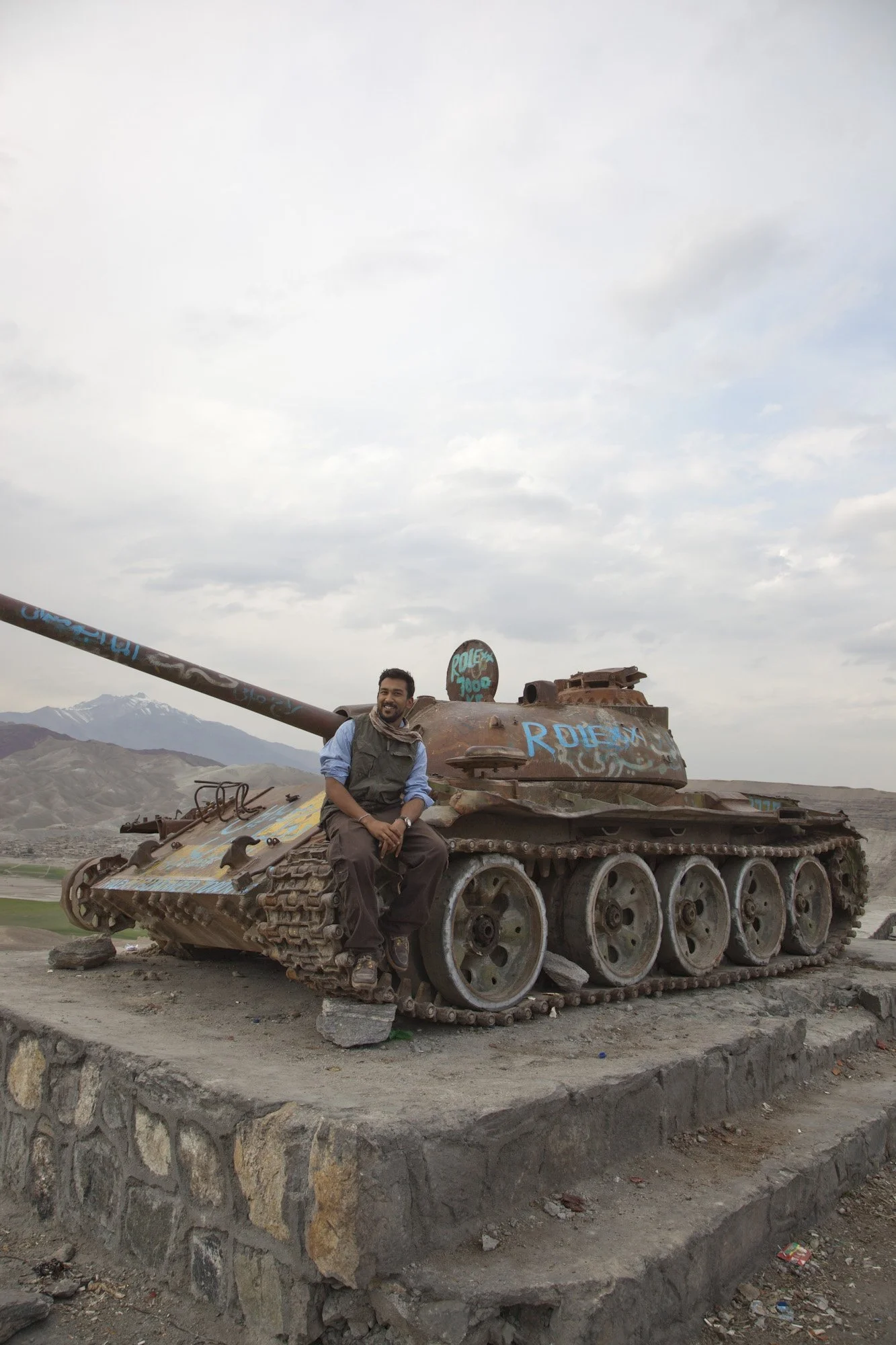 Australian photojournalist Asanka Brendon Ratnayake sitting on a rusted military tank beside the Kabul to Jalalabad road while on assignment in Afghanistan