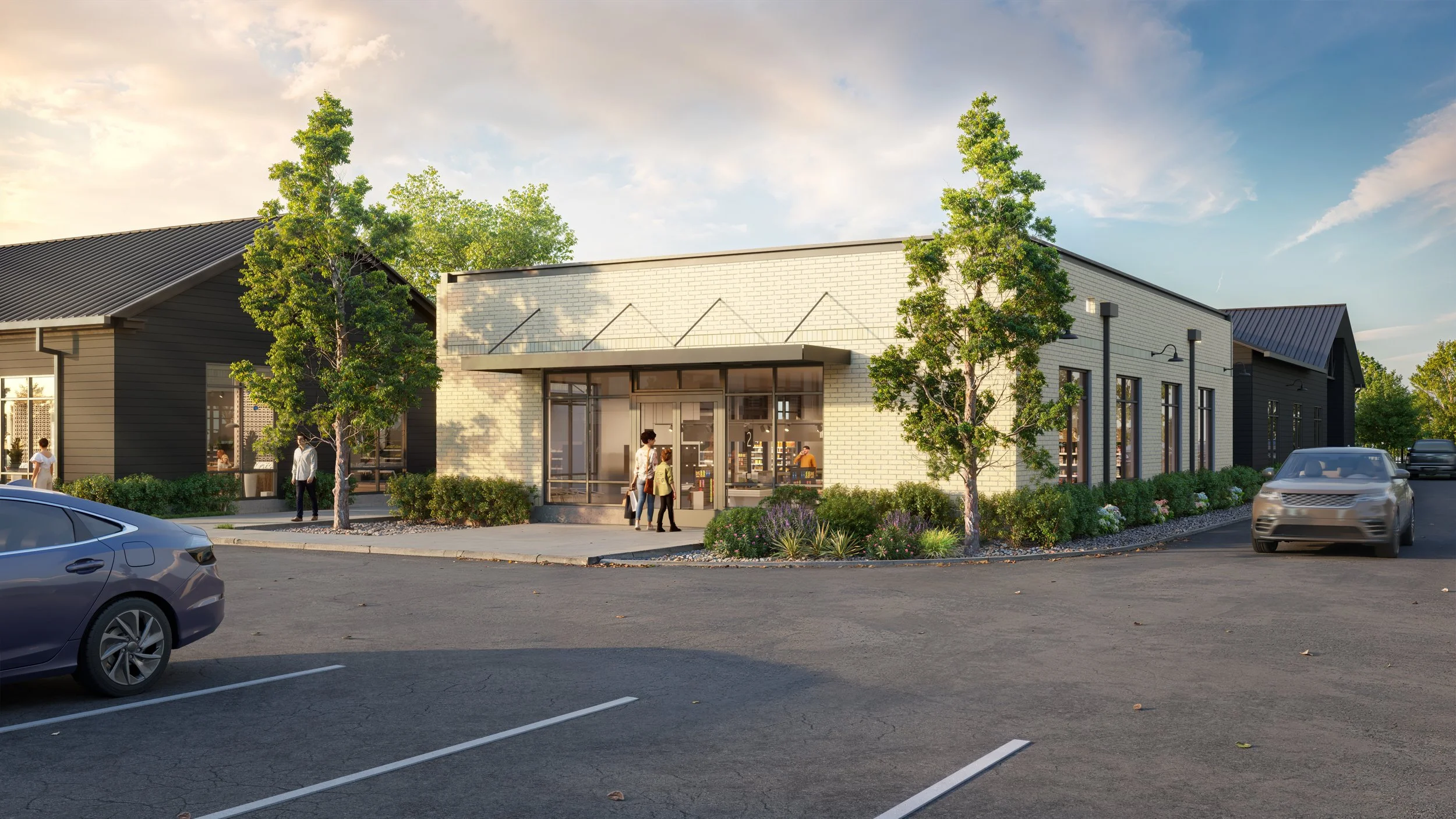 A modern commercial building with large glass windows and a white brick facade, surrounded by greenery and trees. Several people are walking near the entrance, and cars are parked and driving in the parking lot.