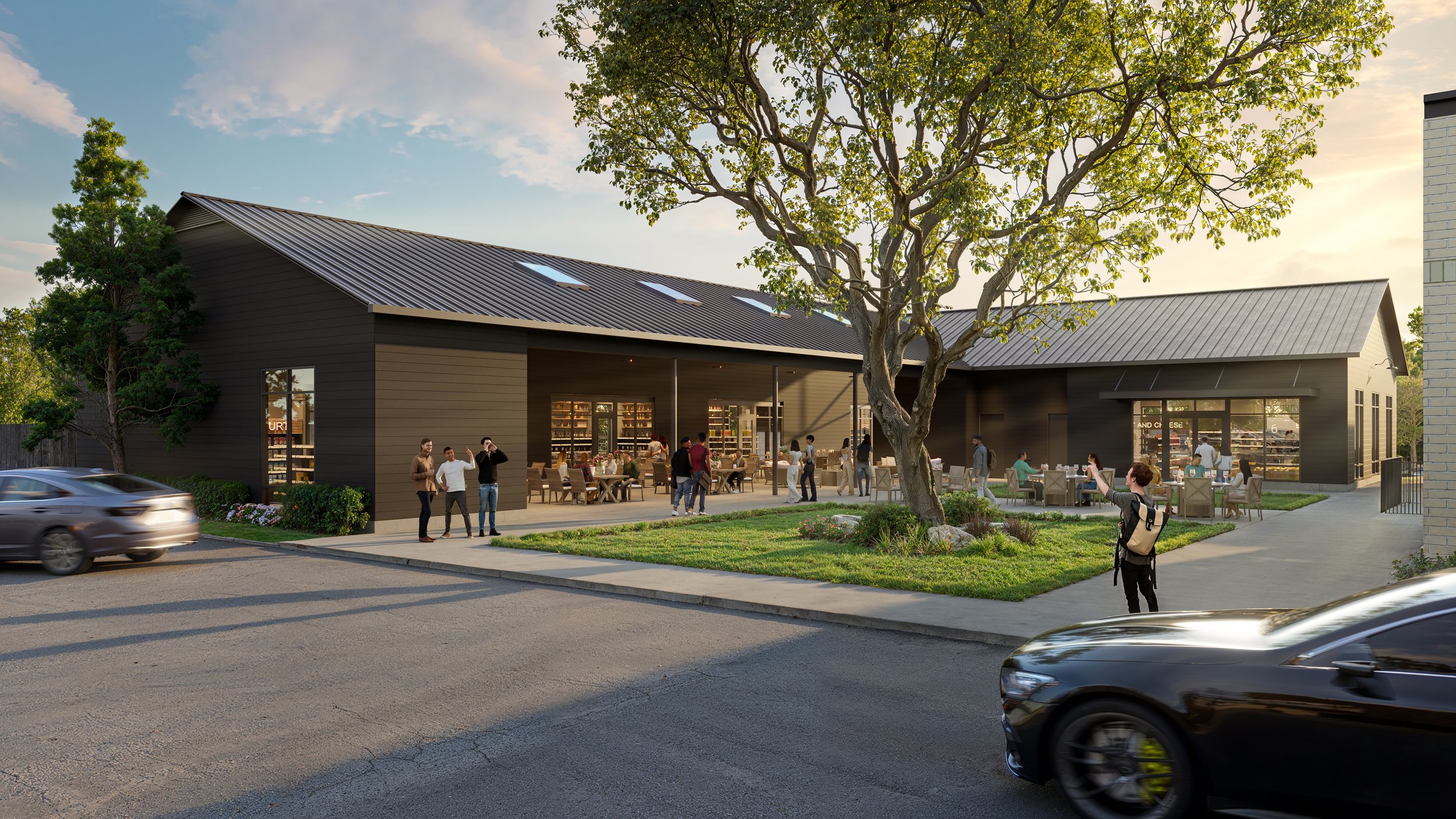 A modern black building with large open patio, people socializing and dining outside. There are trees, a sidewalk, and cars on the street in front.