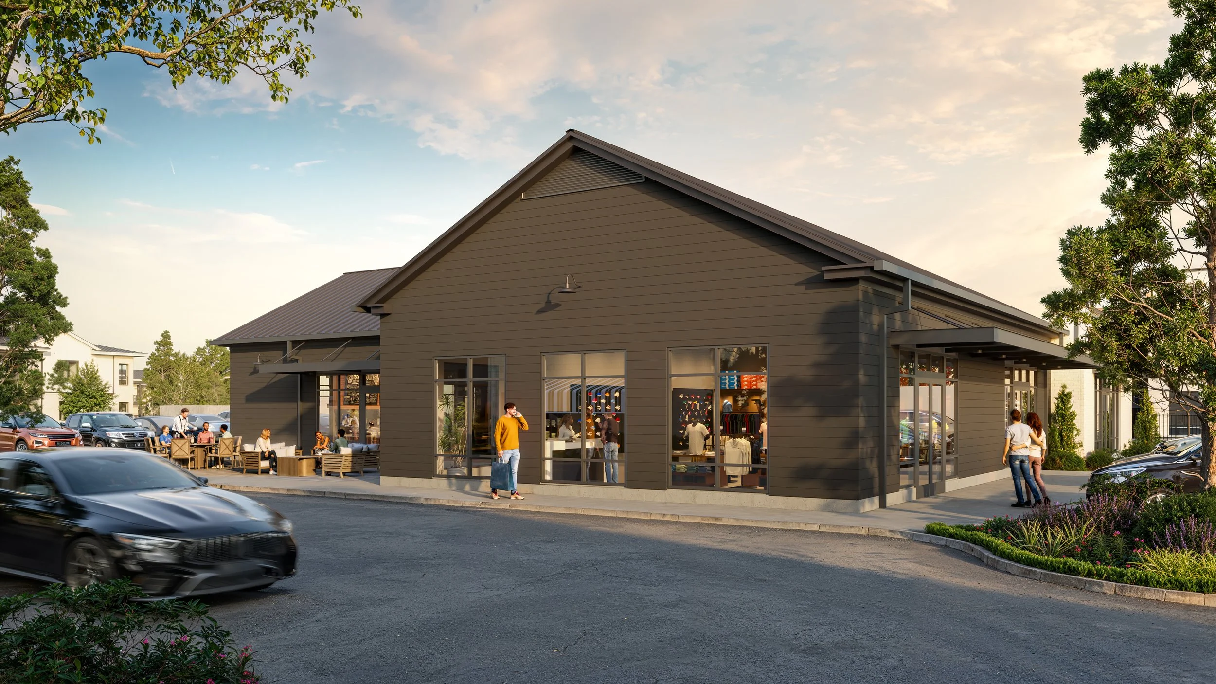 A modern retail store with large windows, people shopping and socializing outside, surrounded by a parking lot and landscaped greenery, under a partly cloudy sky at sunset.