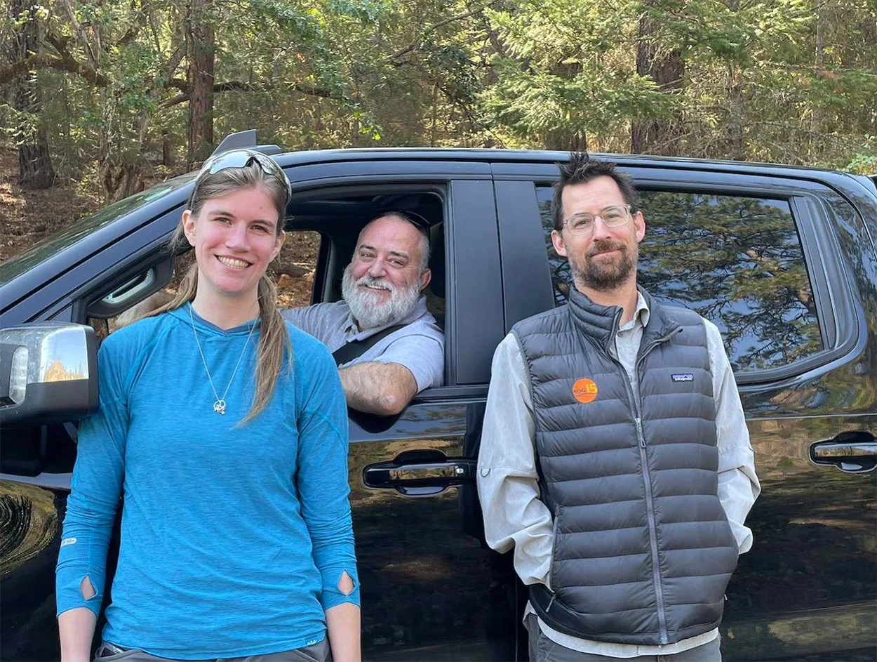 Three RDG team members gathered by a truck at a forested site