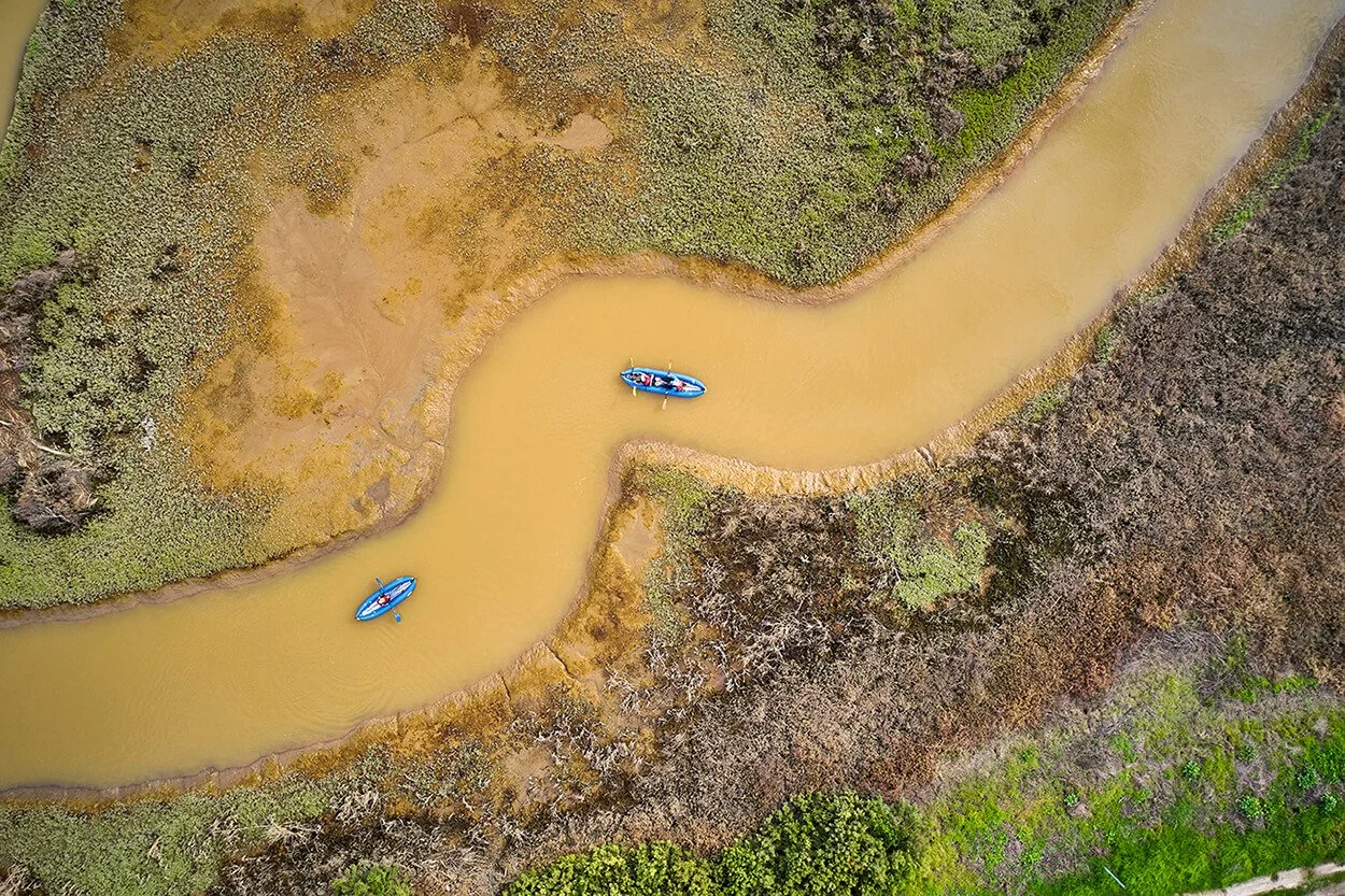 Aerial view of two blue kayaks paddling a winding channel at Pacheco Marsh