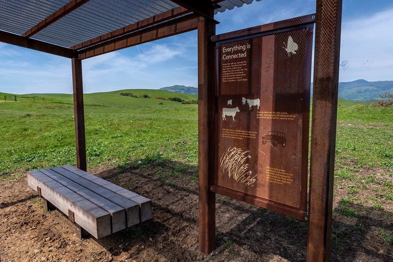 Interpretive shelter with signage and a bench on the grassland at Coyote Ridge
