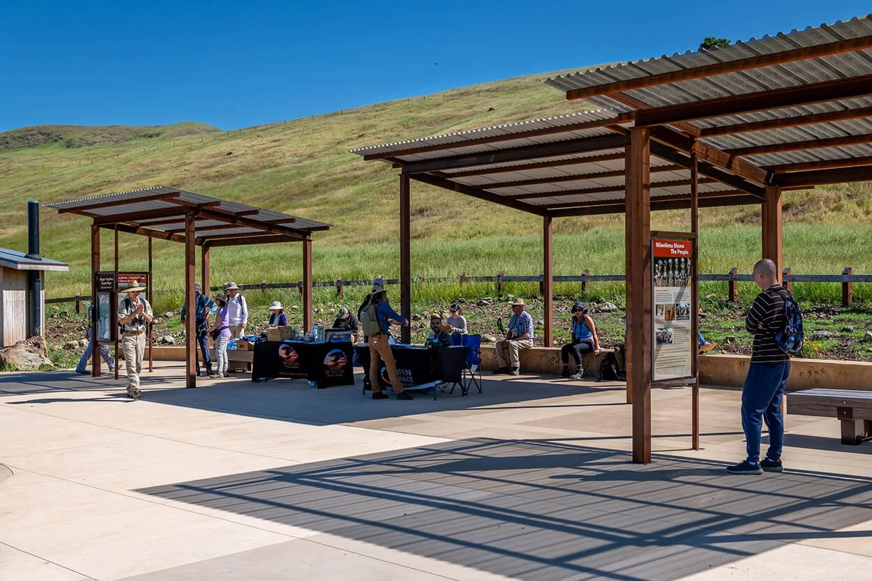 Visitors gathered under shade structures at the Máyyan 'Ooyákma trailhead plaza