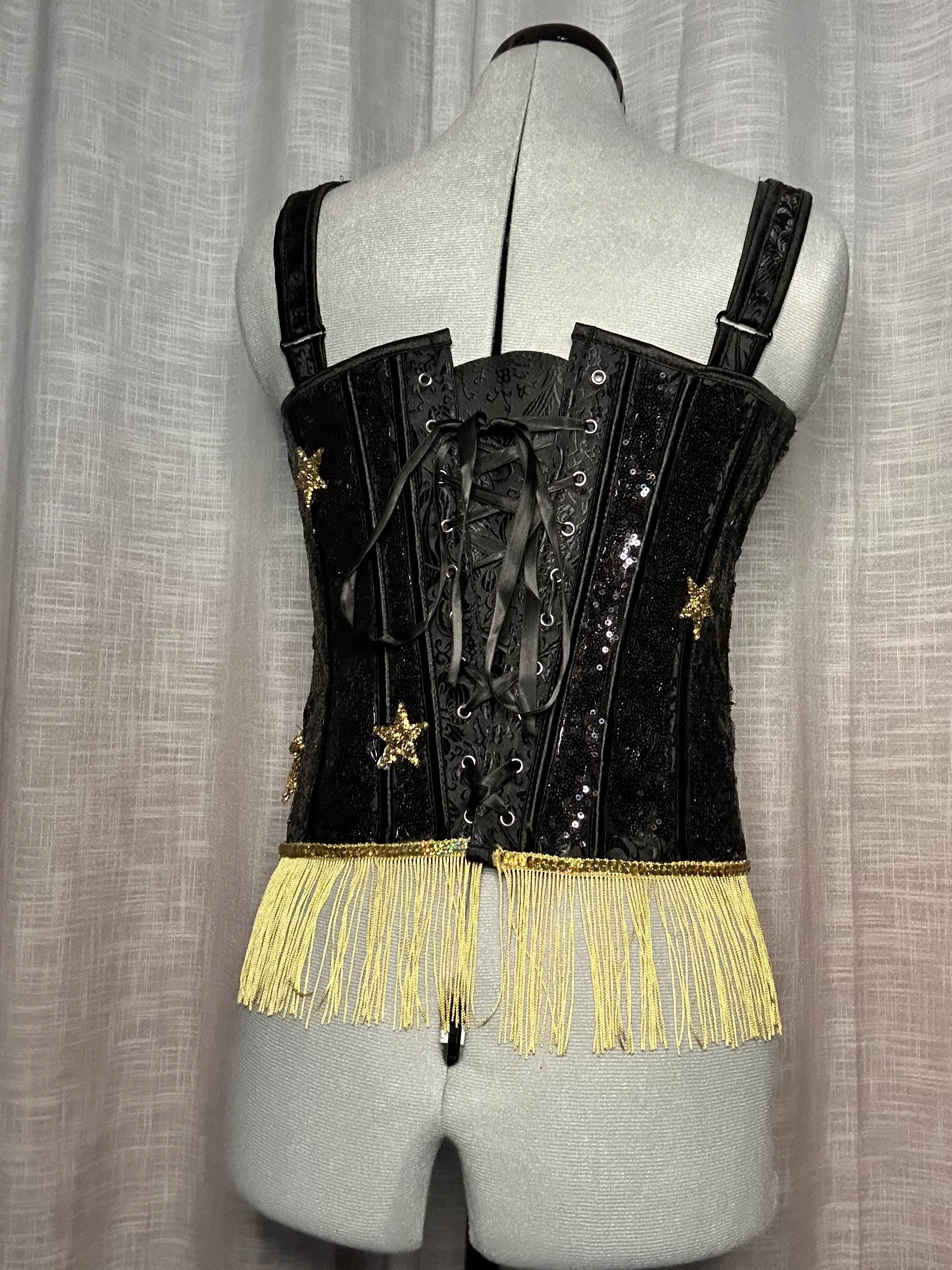 Black corset with gold star and fringe details, displayed on a mannequin with a light gray background.