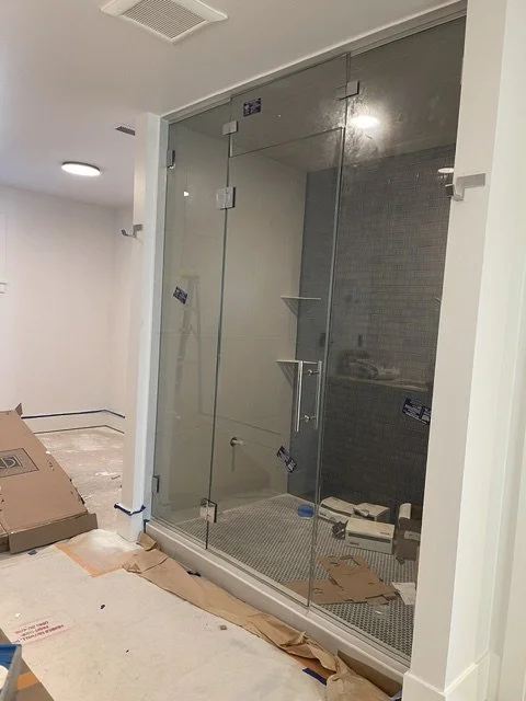 A glass shower enclosure with a sliding door, installed in a bathroom under construction.