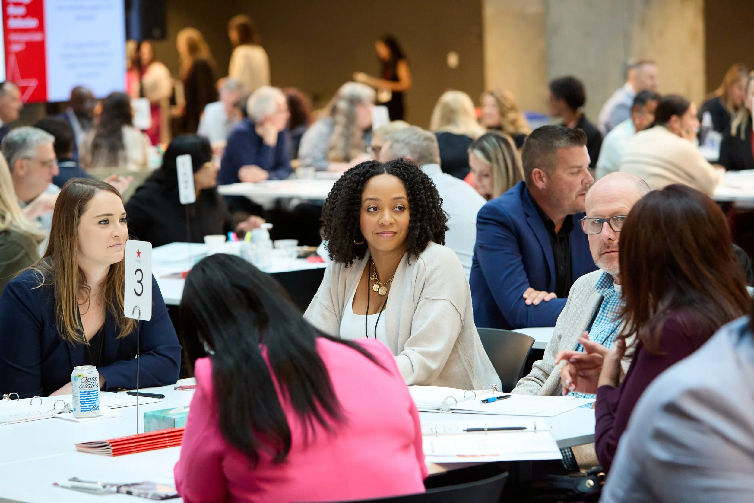 Leaders working in small groups at summit tables during a hands-on workshop session.