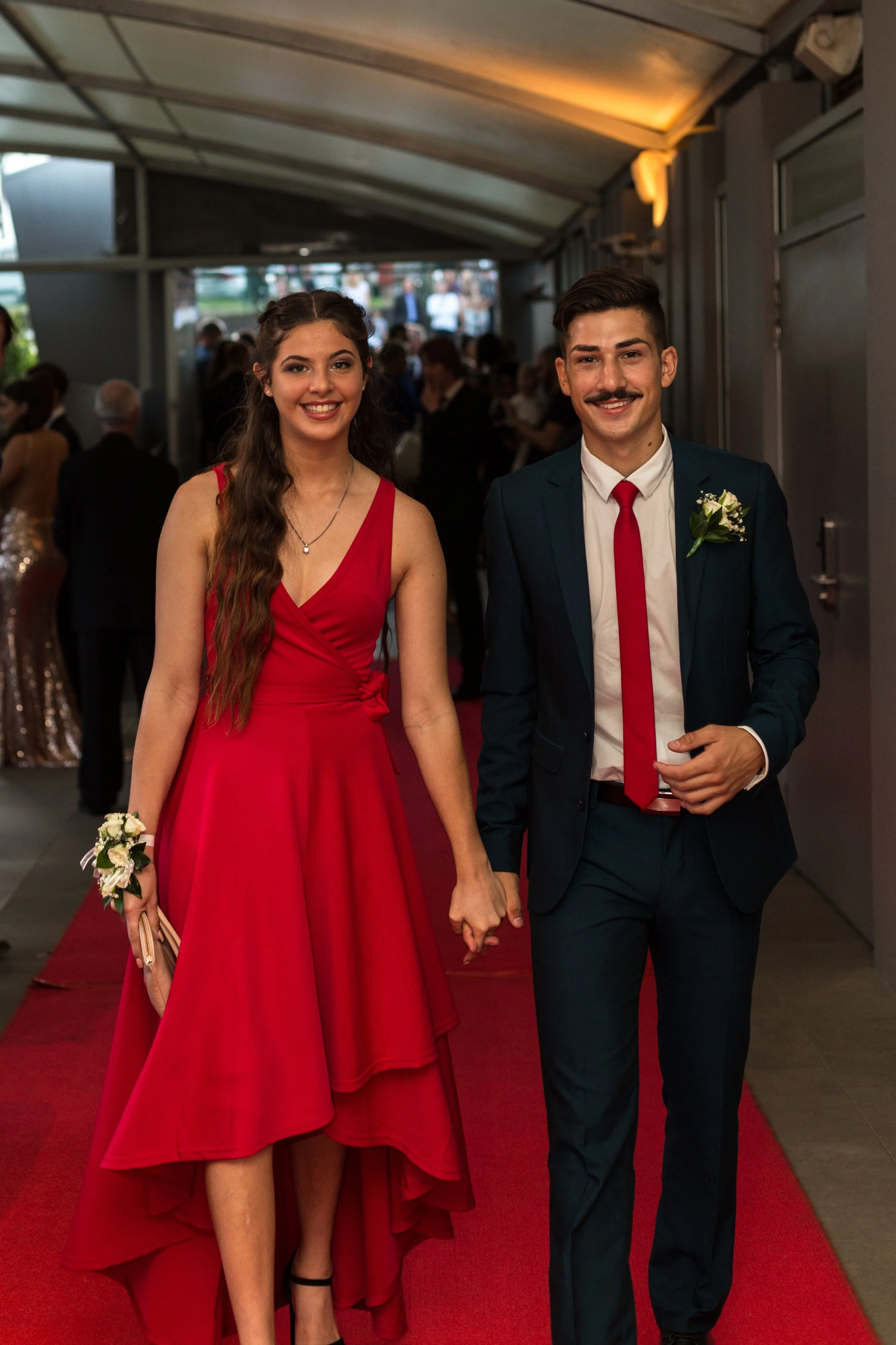 Formal student couple walk down red carpet on arrival at Southport Sharks.