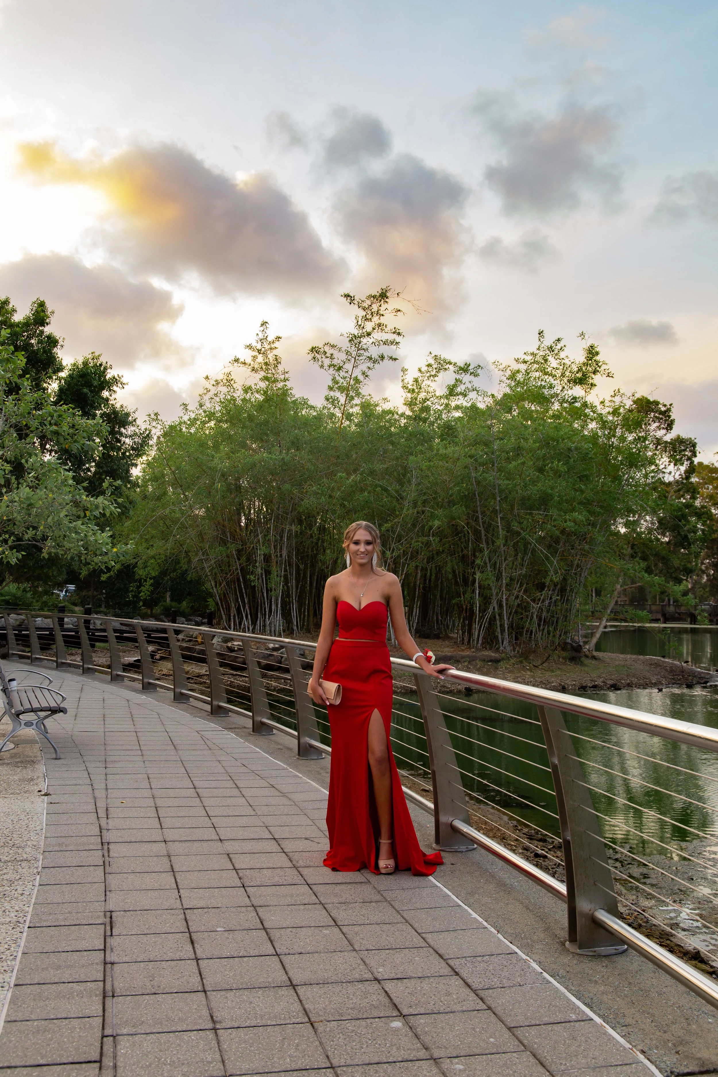 Formal student in red dress ready for their formal with stunning colours in sky at Benowa Botanical Gardens.