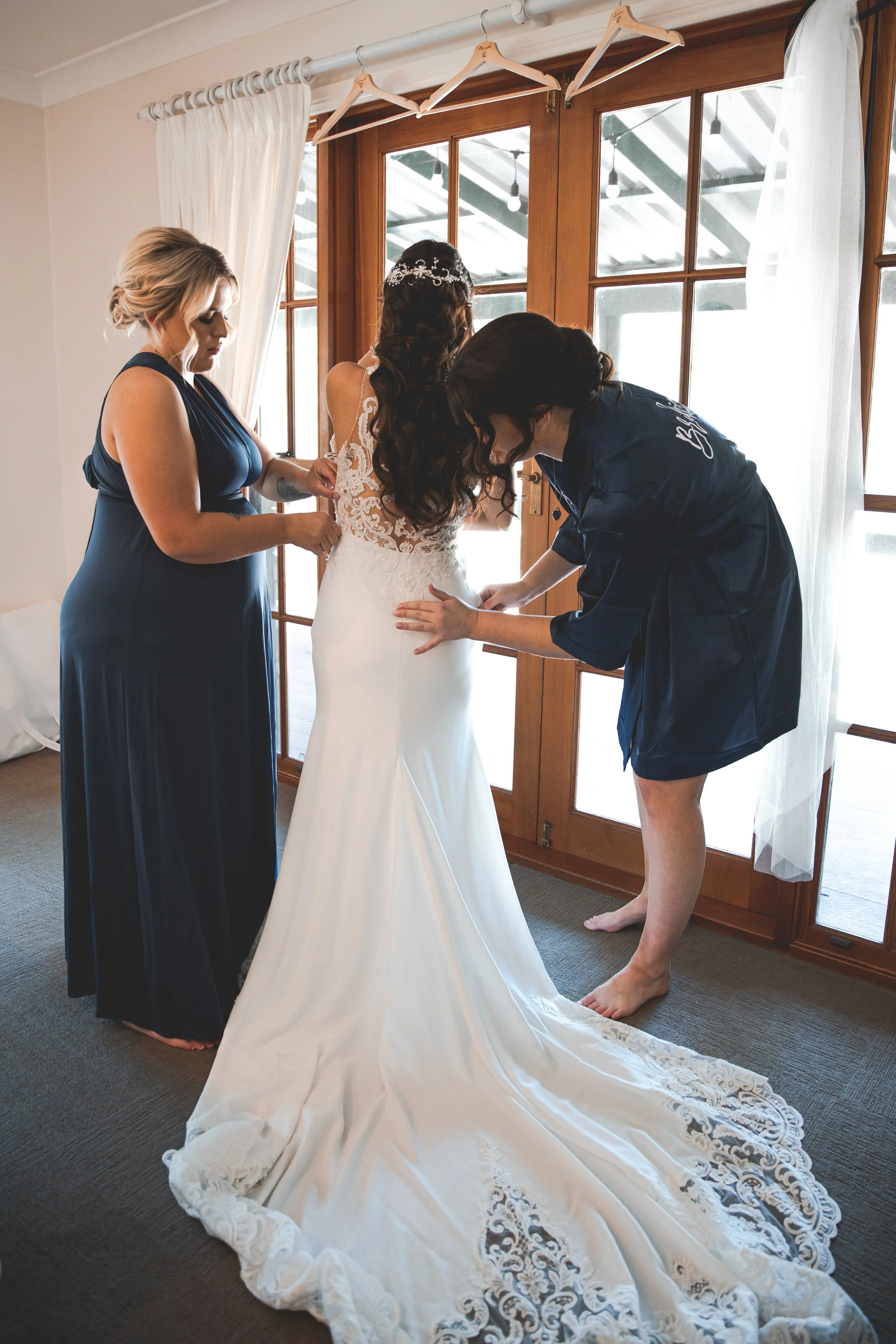 Bride getting in wedding gown with bridesmaids at Coolabah Downs Private Estate, Bridal Homestead. 