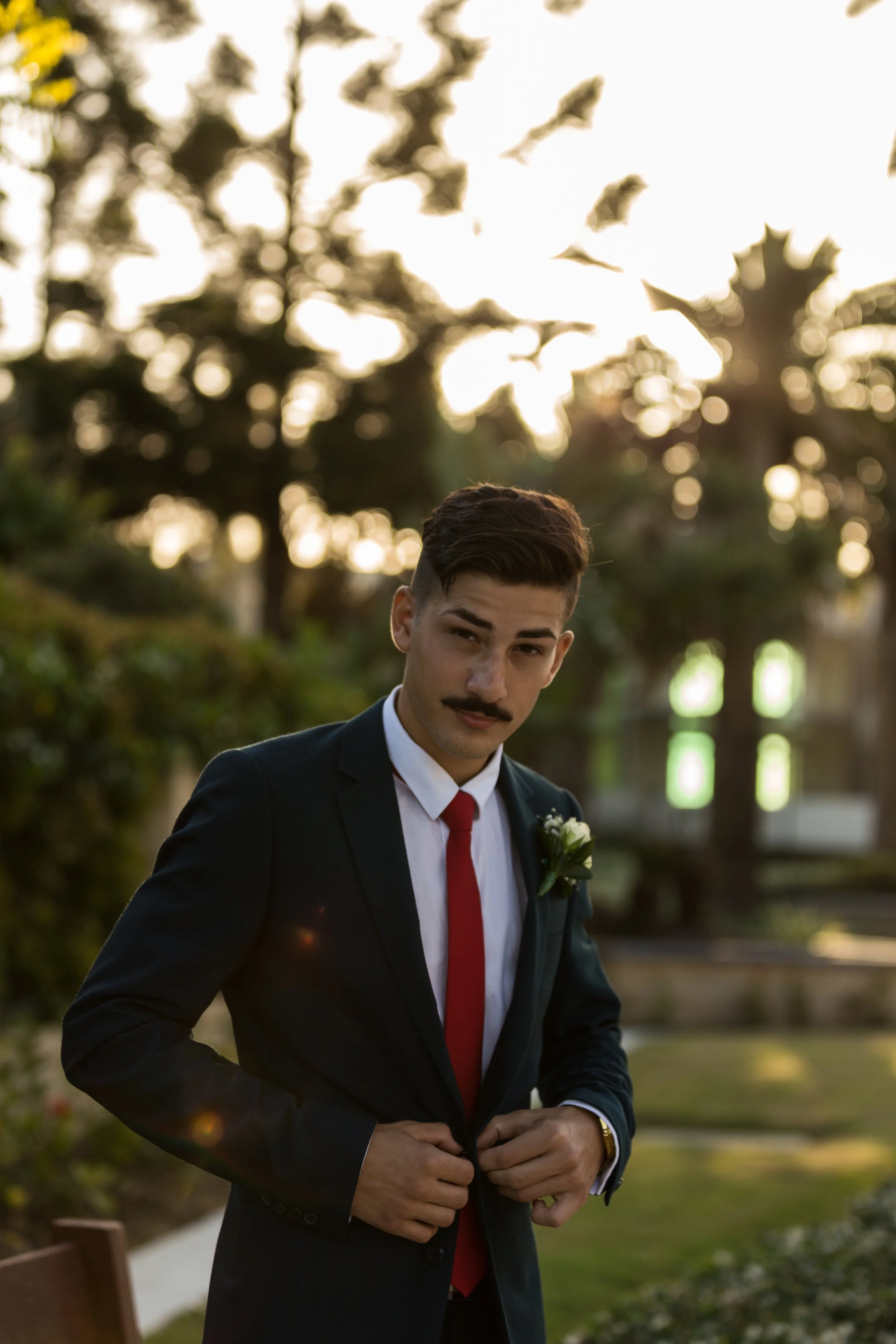 Male stands in garden for a portrait dressed in suit and tie with stunning natural golden light at Sovereign Island.